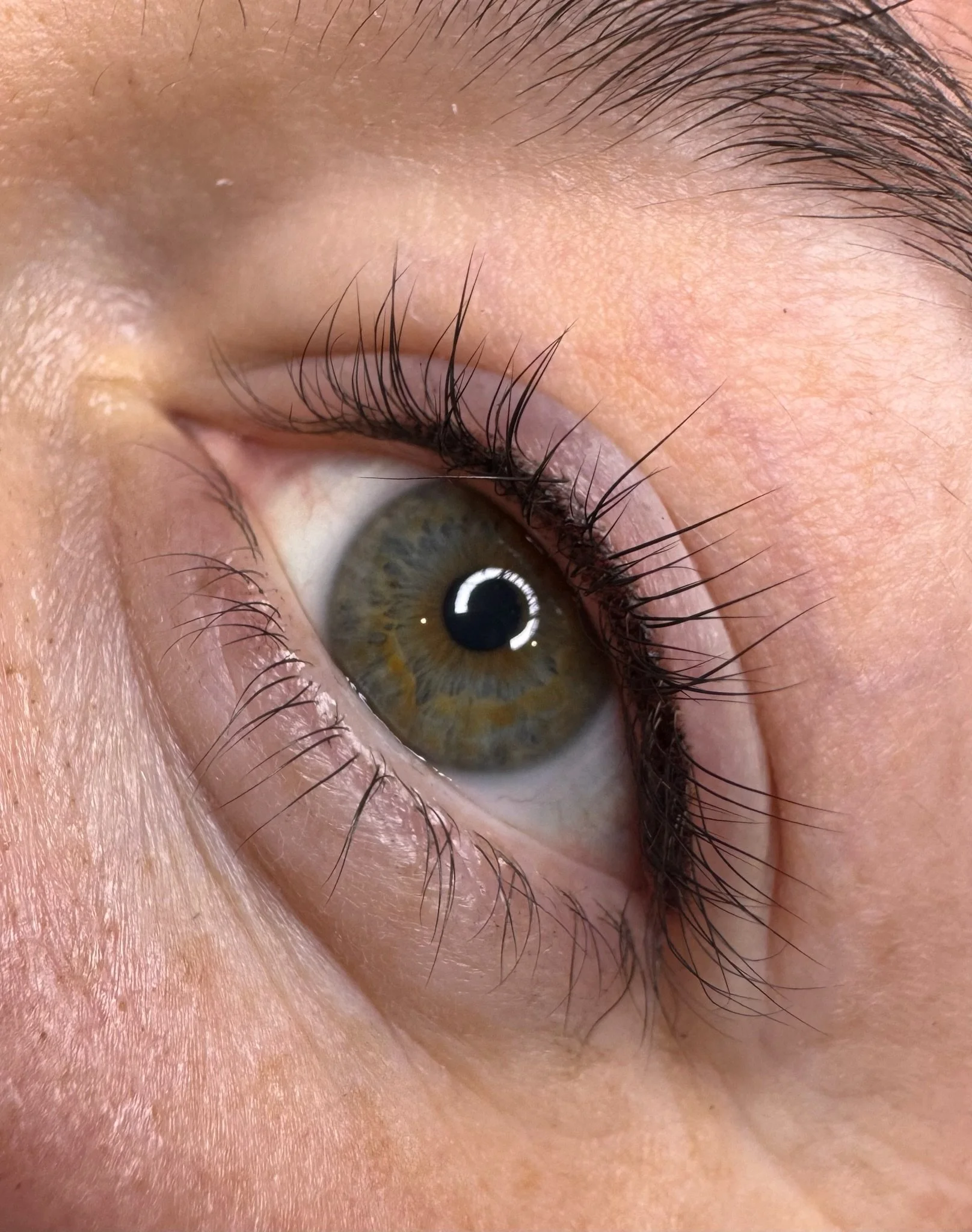 Close-up of a human eye with brown irises, long eyelashes, and detailed skin texture.