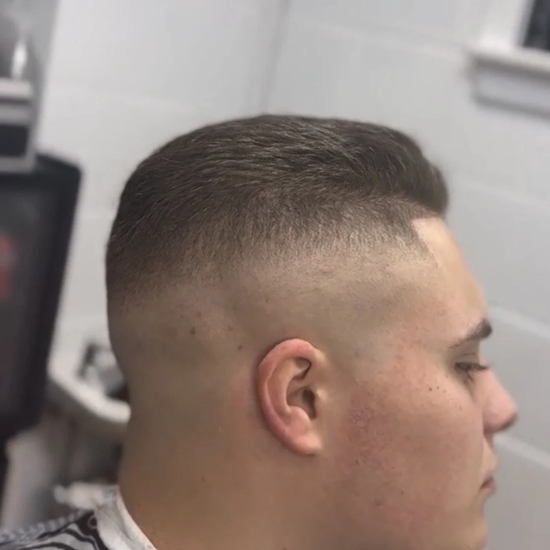 Close-up of a young man's head with a fade haircut, showing the gradual transition from short sides to slightly longer hair on top.