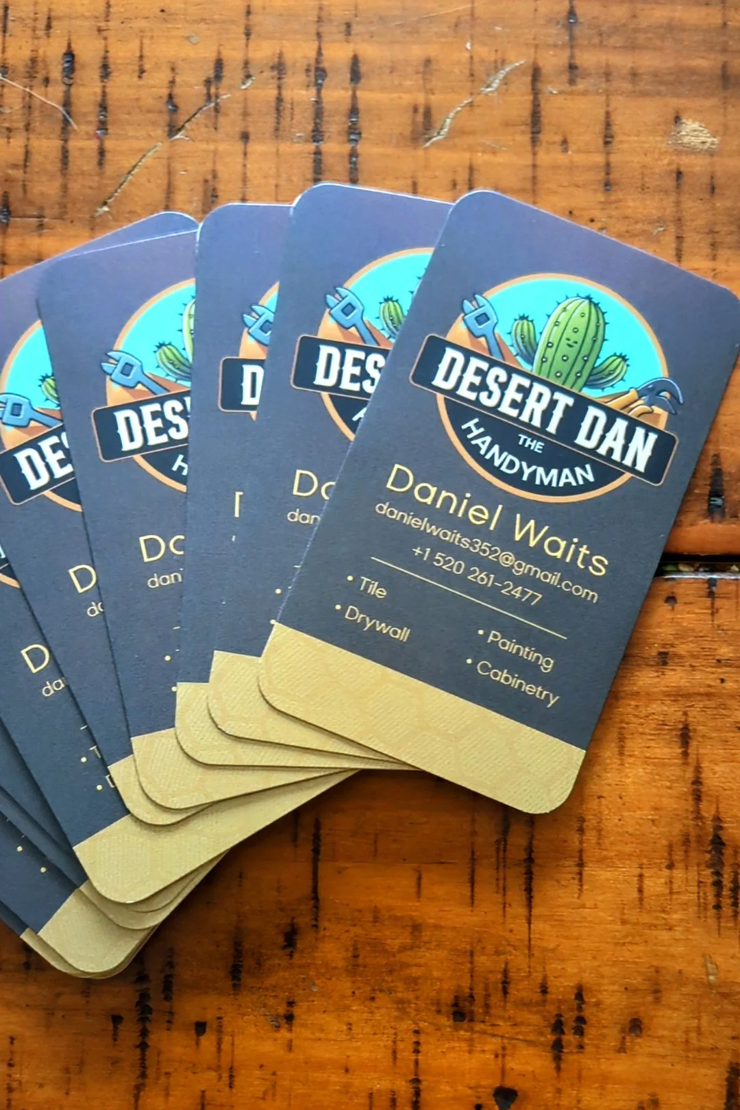 Stack of business cards for Desert Dan the Handyman, featuring a cactus and wrench logo, with contact information and services listed.