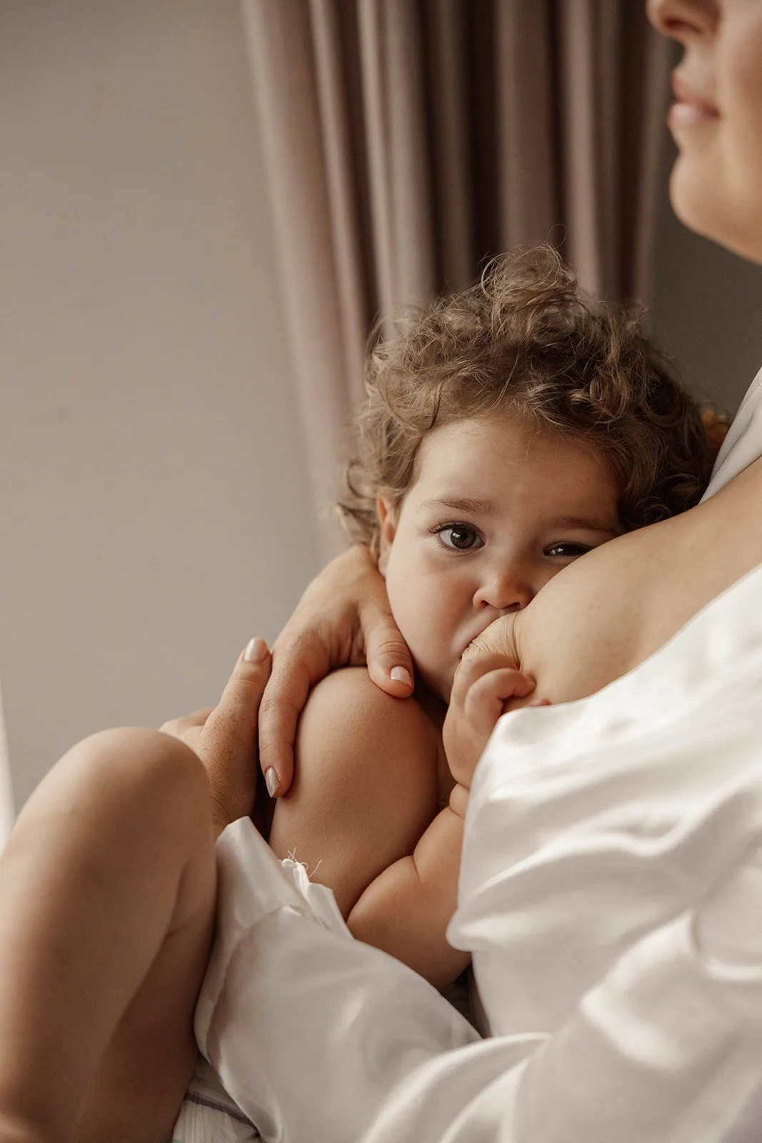 Een jong kind dat borstvoeding krijgt van een vrouw, in een intieme en rustige setting.