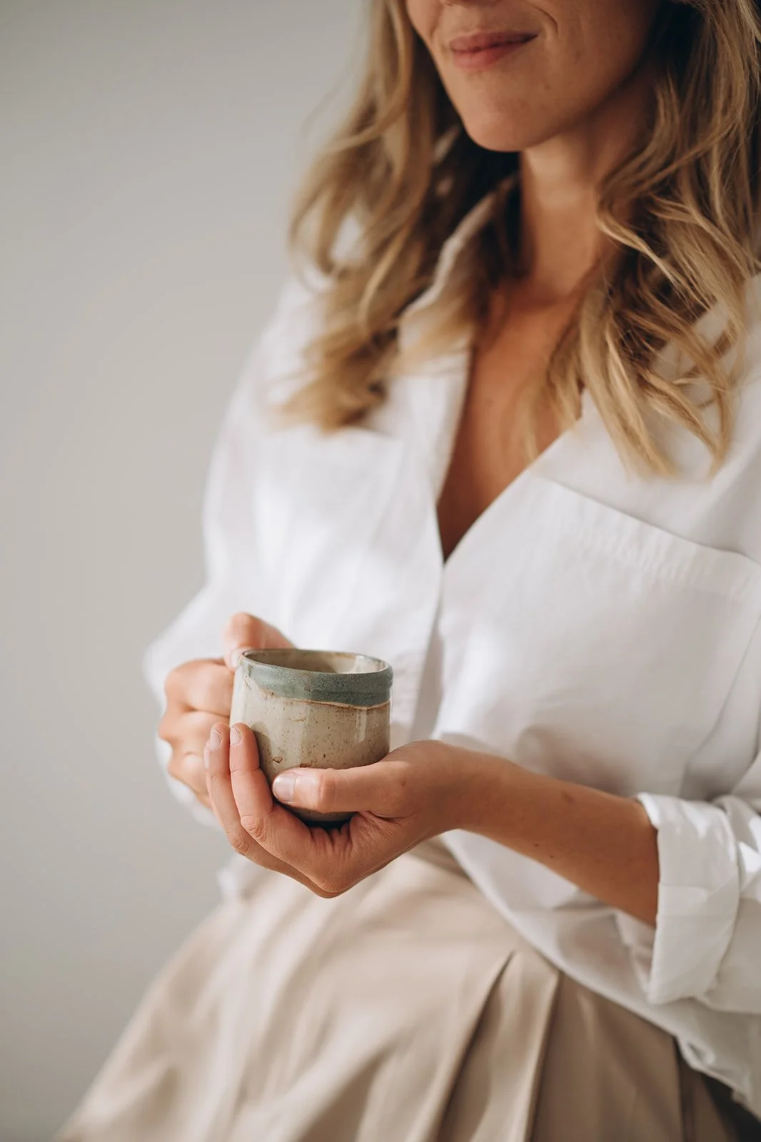 Een vrouw houdt een keramieken kopje met koffie of thee vast.