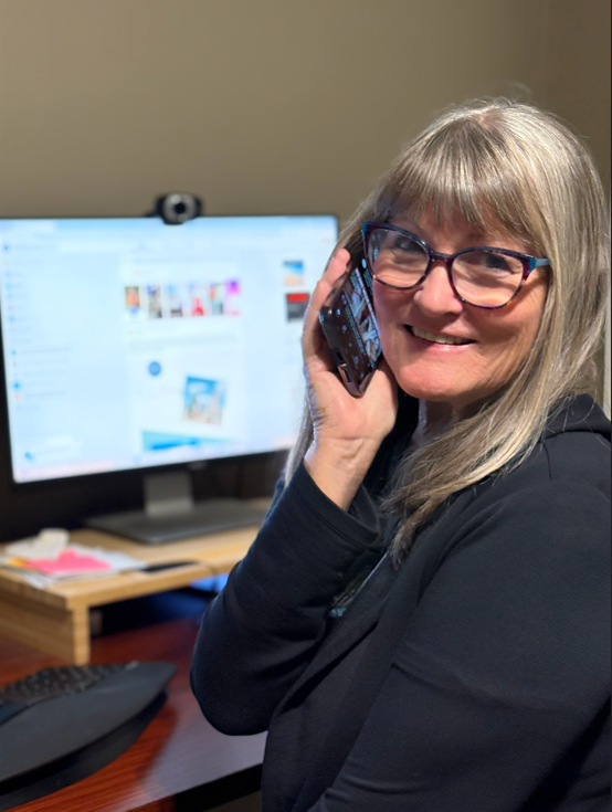 Laura Varnau, travel agent with wishes and waves travel, talking on the phone with her desk and computer in the background