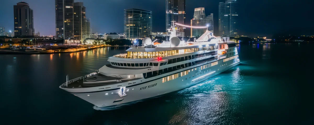 windstar's star seeker at night in a port with a big city in the background