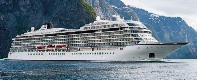 viking ocean cruise ship on the water with snow-capped mountains in the background