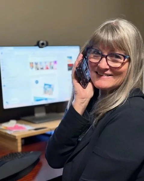 Laura sitting at her desk talking on the phone