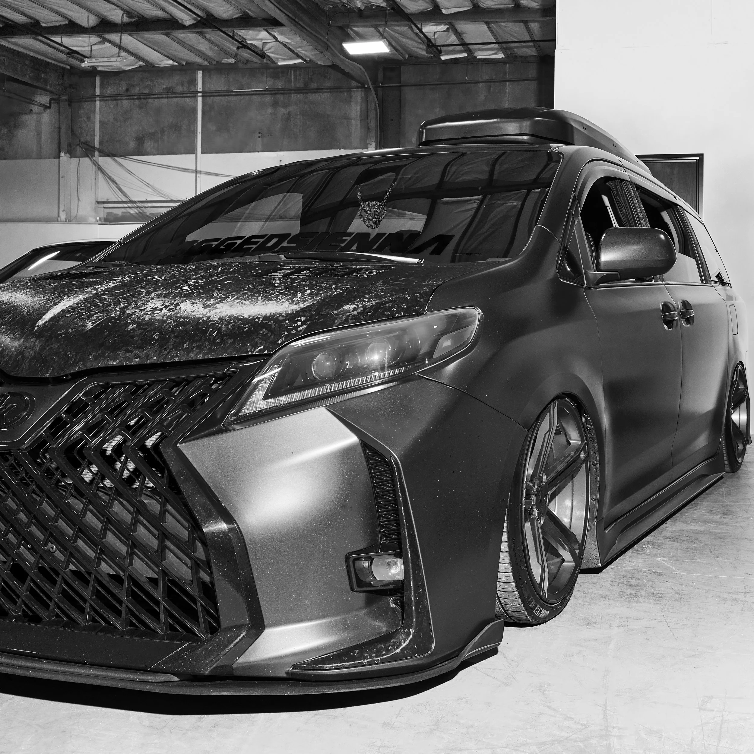 A black and silver modern sedan with custom wheels and a lowered suspension parked indoors.
