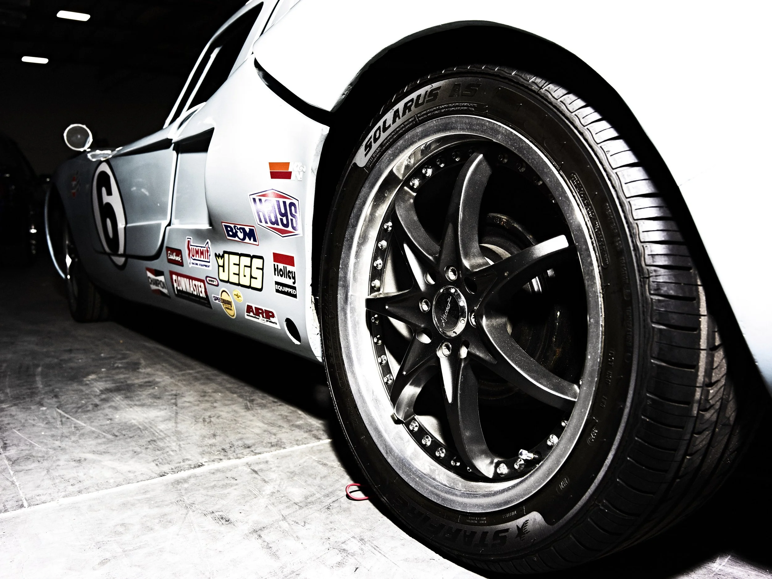 Close-up of a racing car's front wheel with decals and racing stickers on the side.