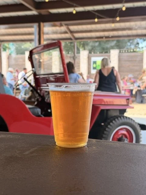 cup of beer on a bar in front of red jeep