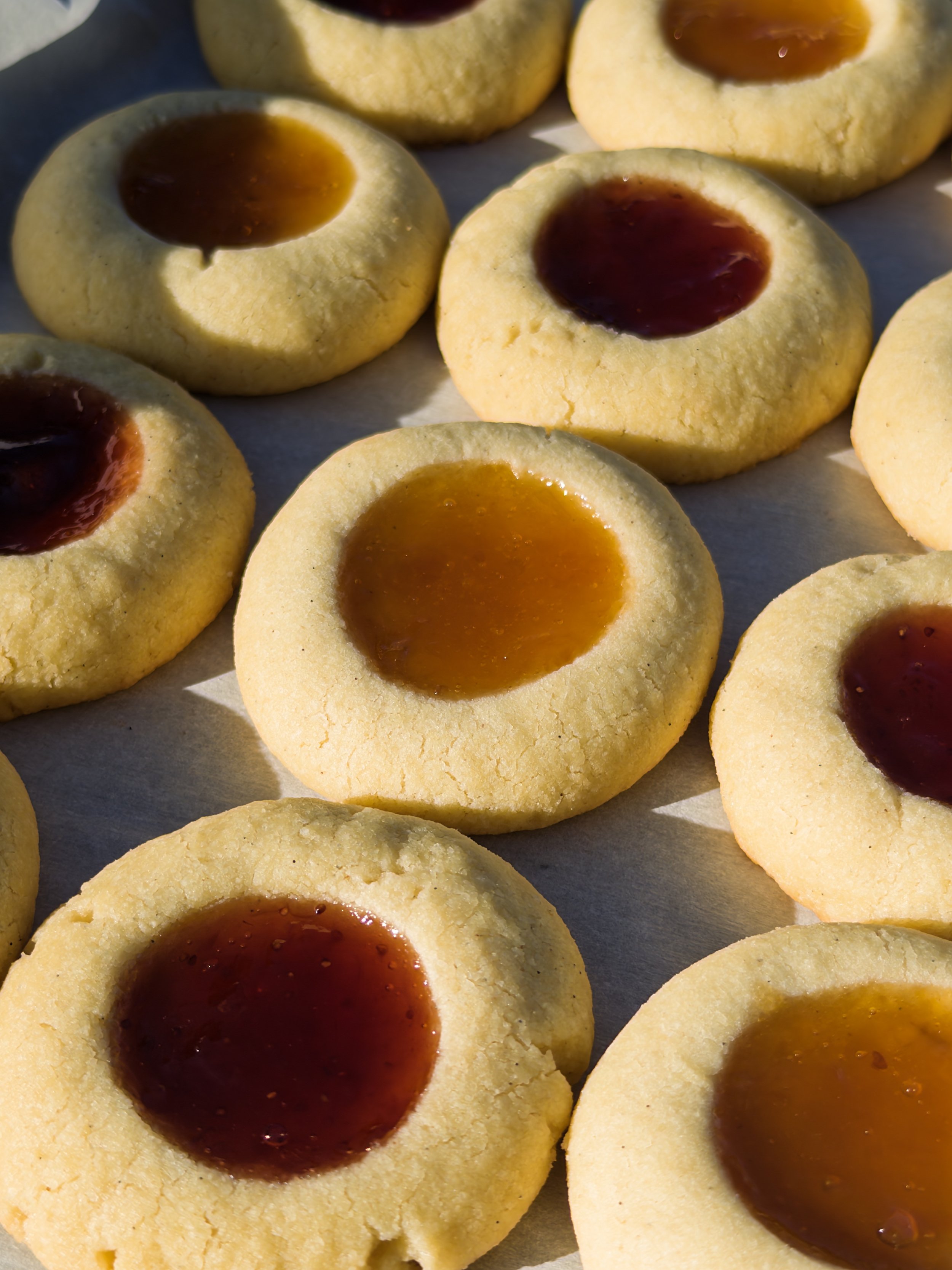 Close-up of thumbprint cookies with caramel and raspberry jam centers.