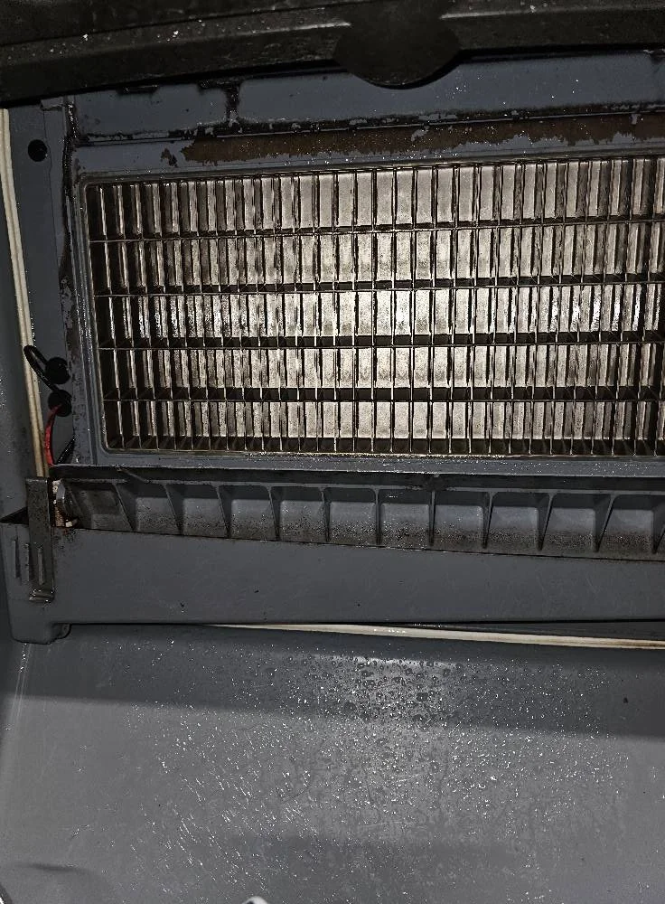 Close-up view of the inside of a refrigerator or freezer, showing metal racks and some frost or ice buildup.