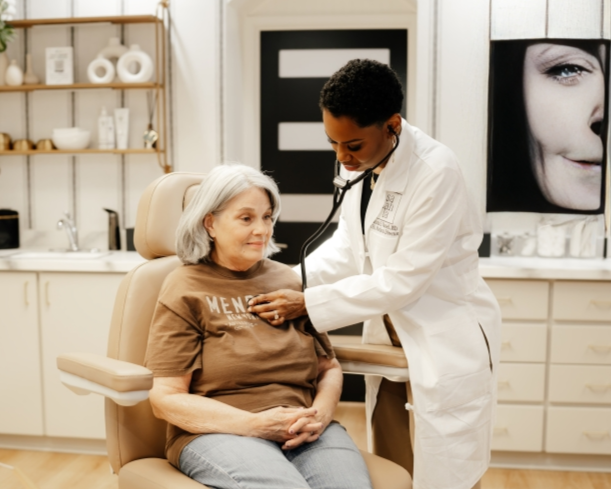 A doctor examines an elderly woman with a stethoscope in a medical office.