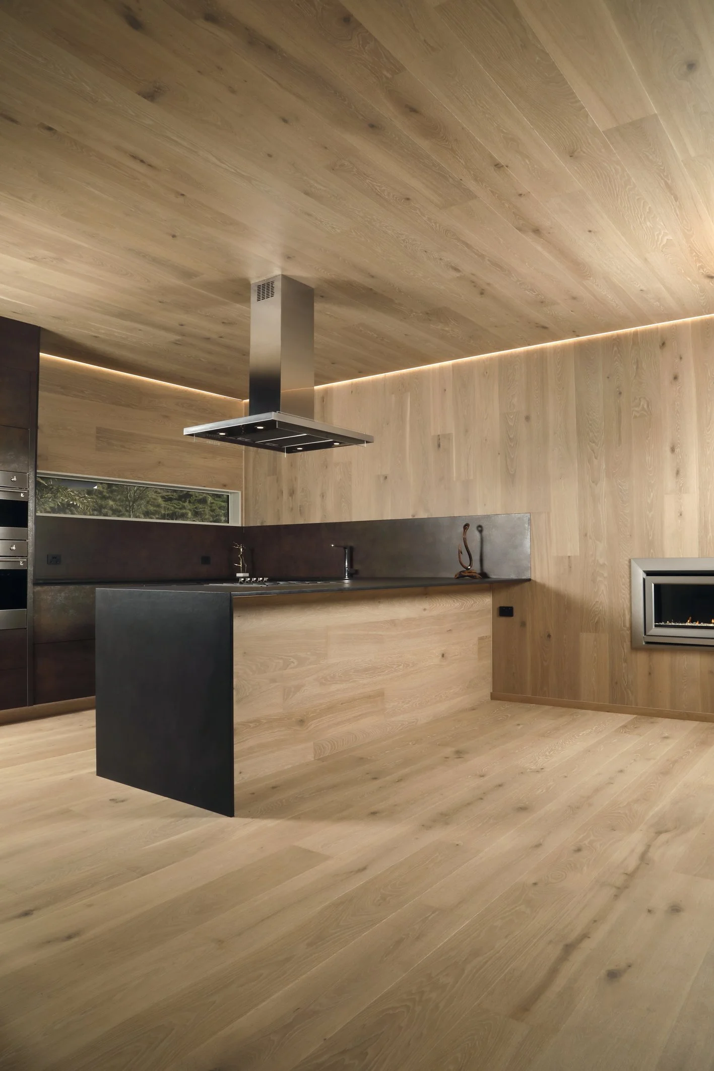 Modern kitchen with wooden walls, ceiling, and floor, a black kitchen island, and a built-in fireplace.
