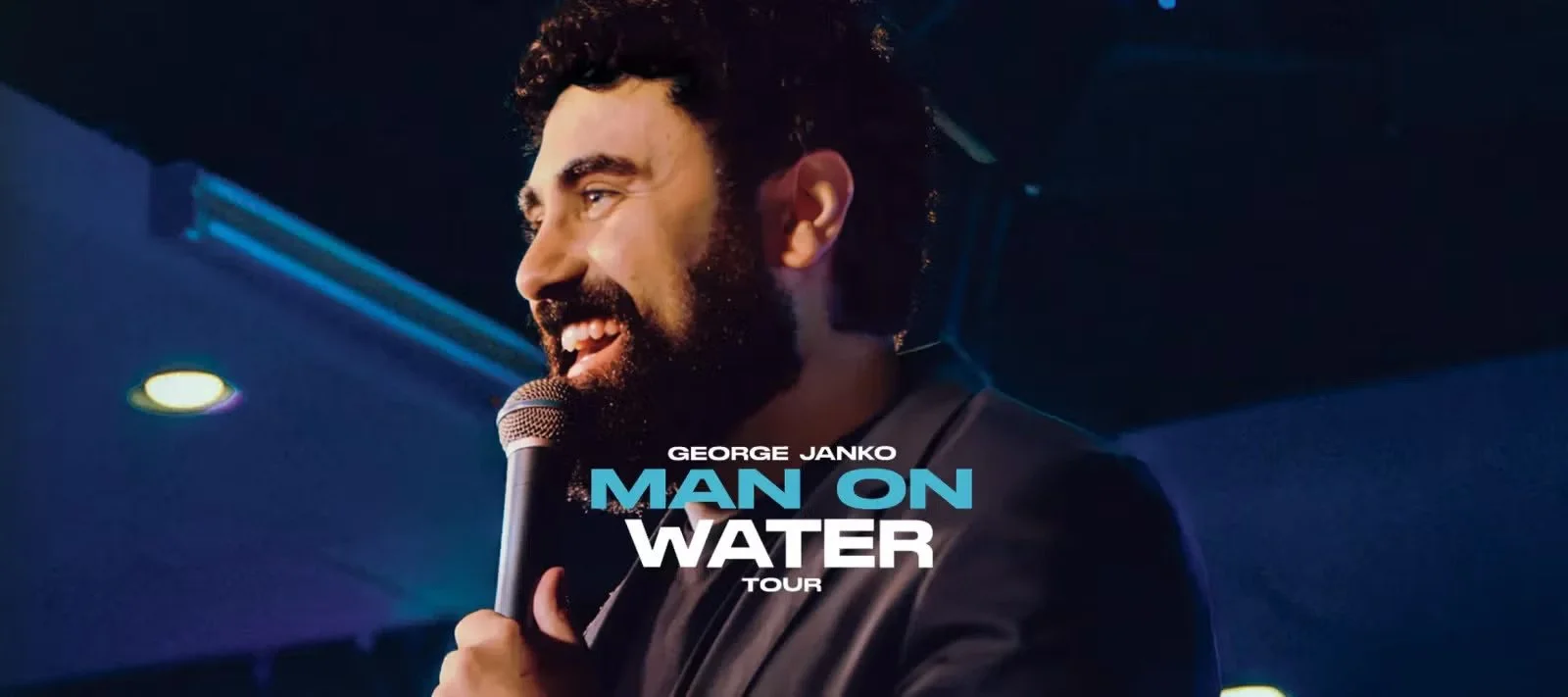 George Janko smiling and holding a microphone during his Man on Water tour.