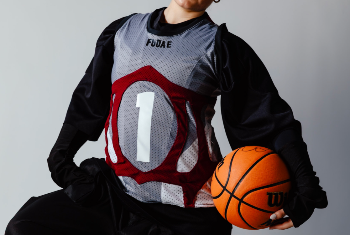 A person in a basketball uniform holding an orange Wilson basketball.