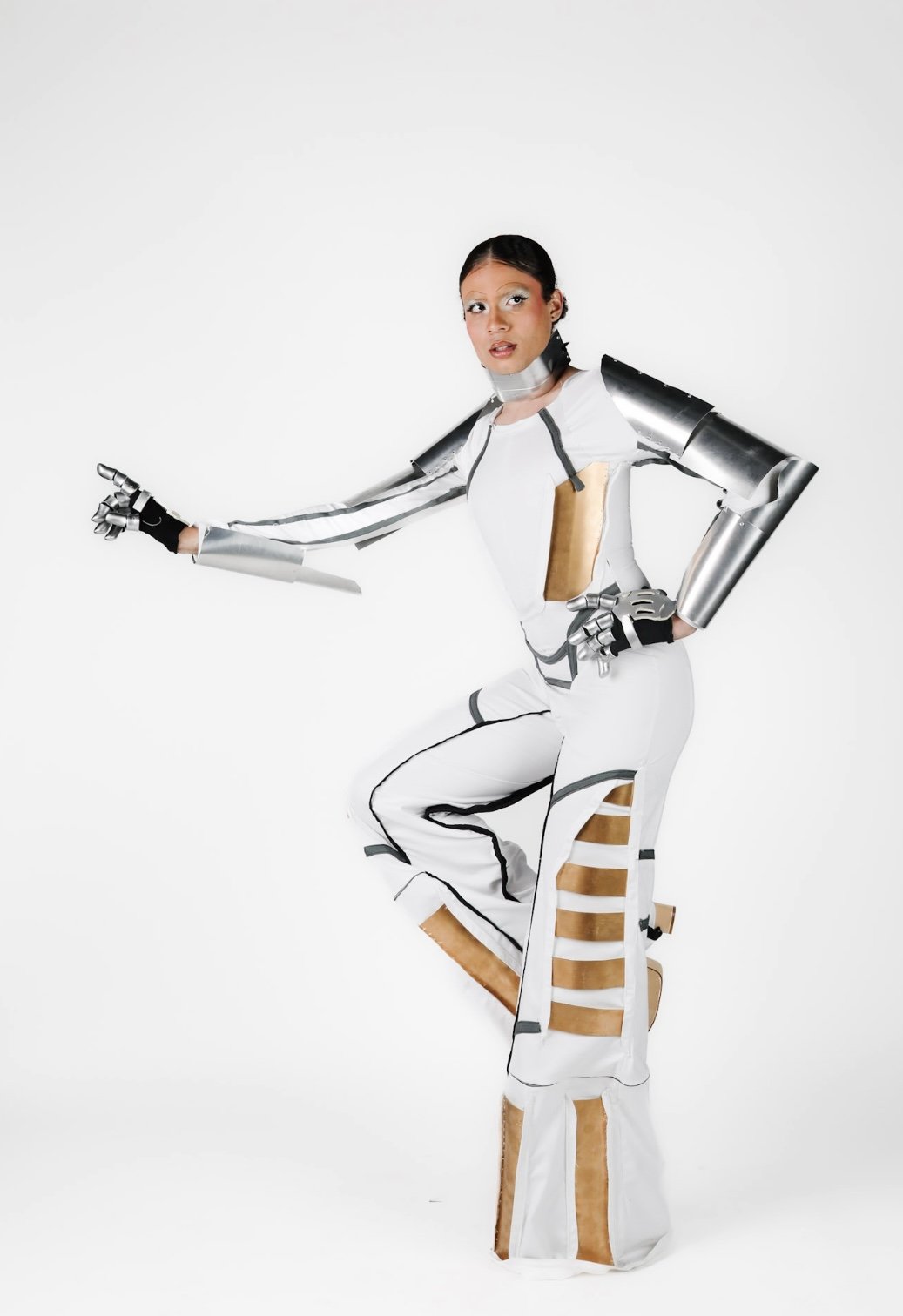 Person dressed in futuristic metallic and white costume with armor elements against white background