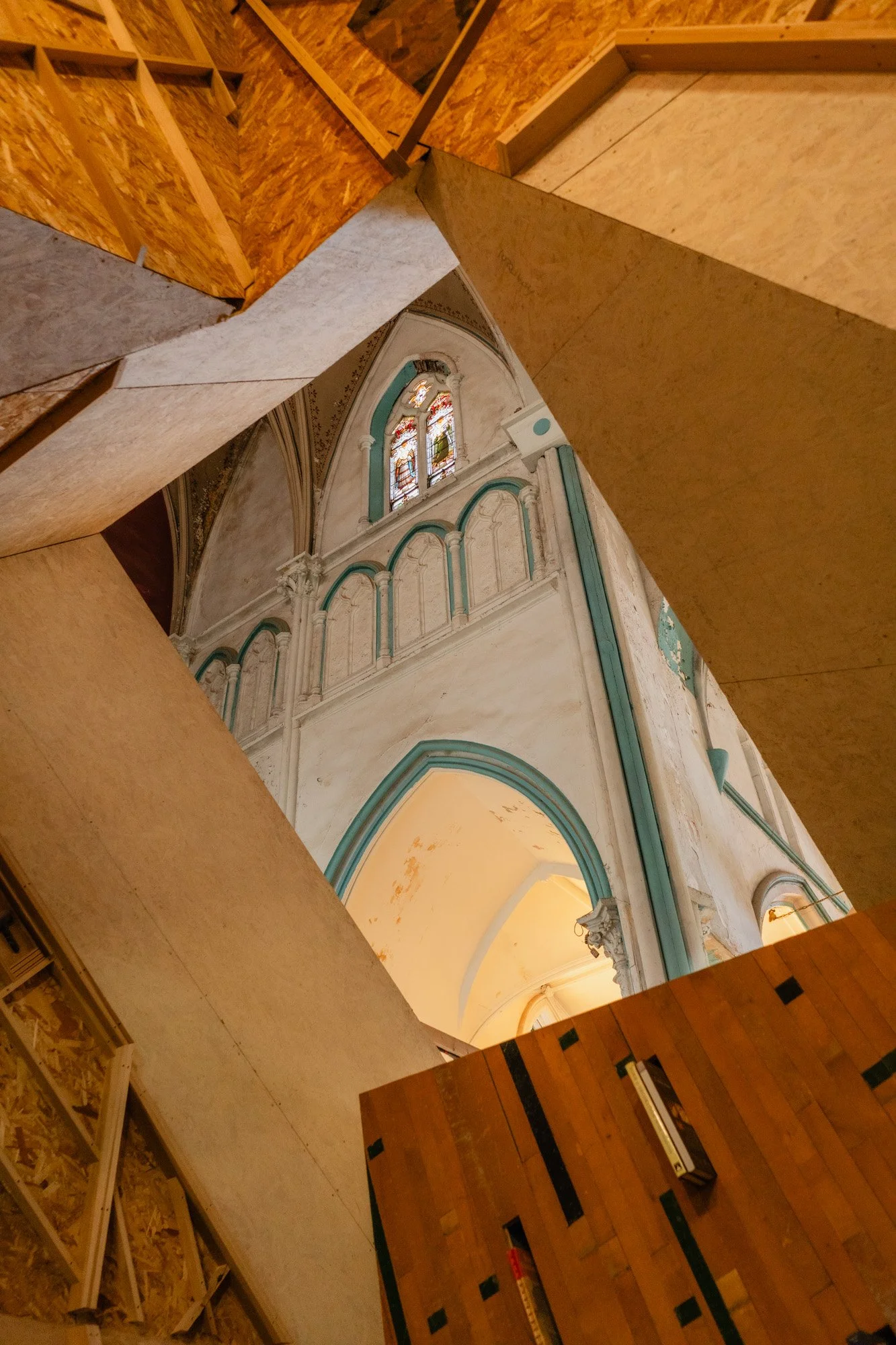 Interior view of a church with stained glass windows, white walls, and wooden accents.