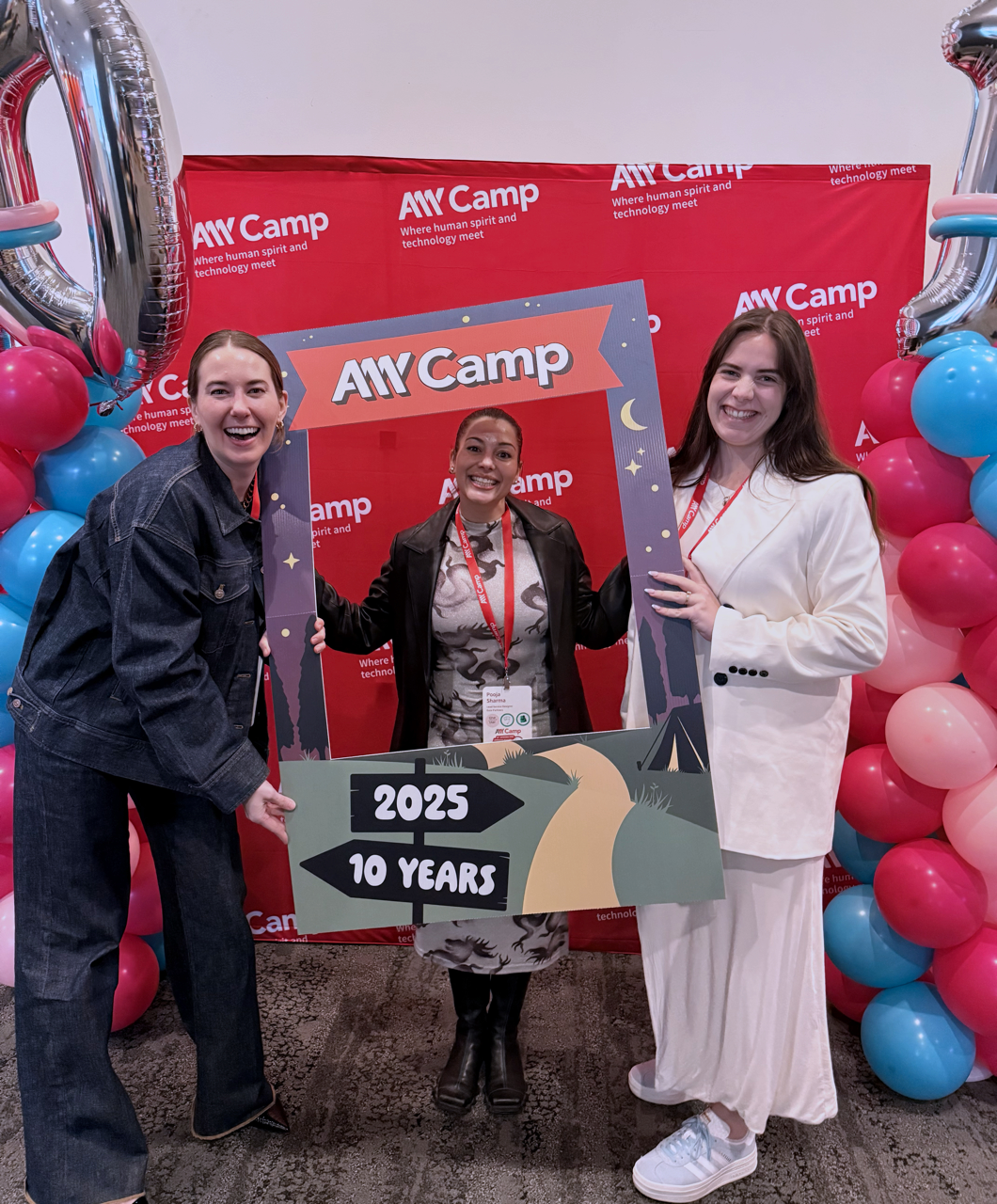 three women standing in front of a11y camp 2025 sign