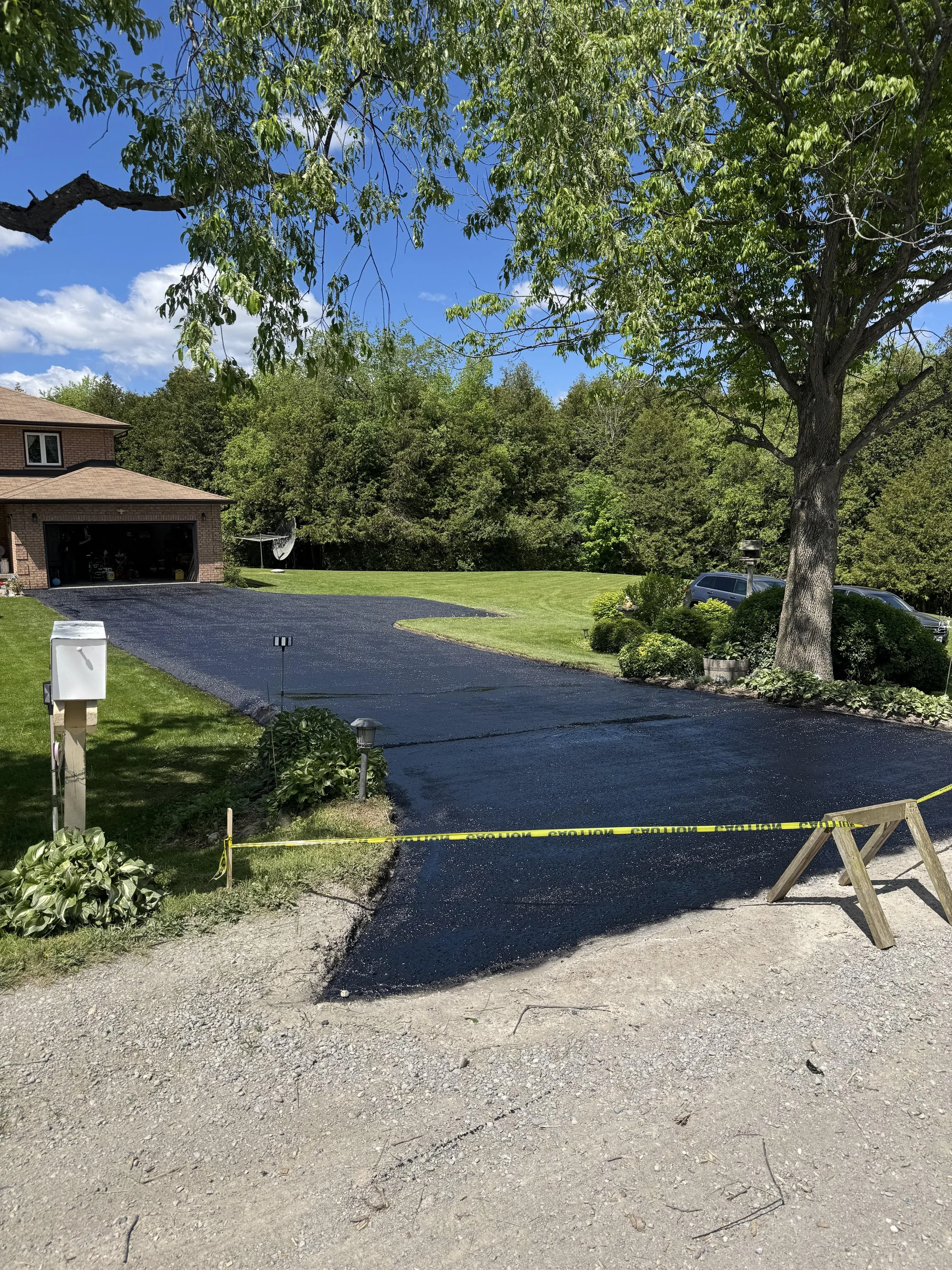 Newly sealed black asphalt driveway with 2 layers of sealant, cold patch, and crack fill in Beaverton, Ontario