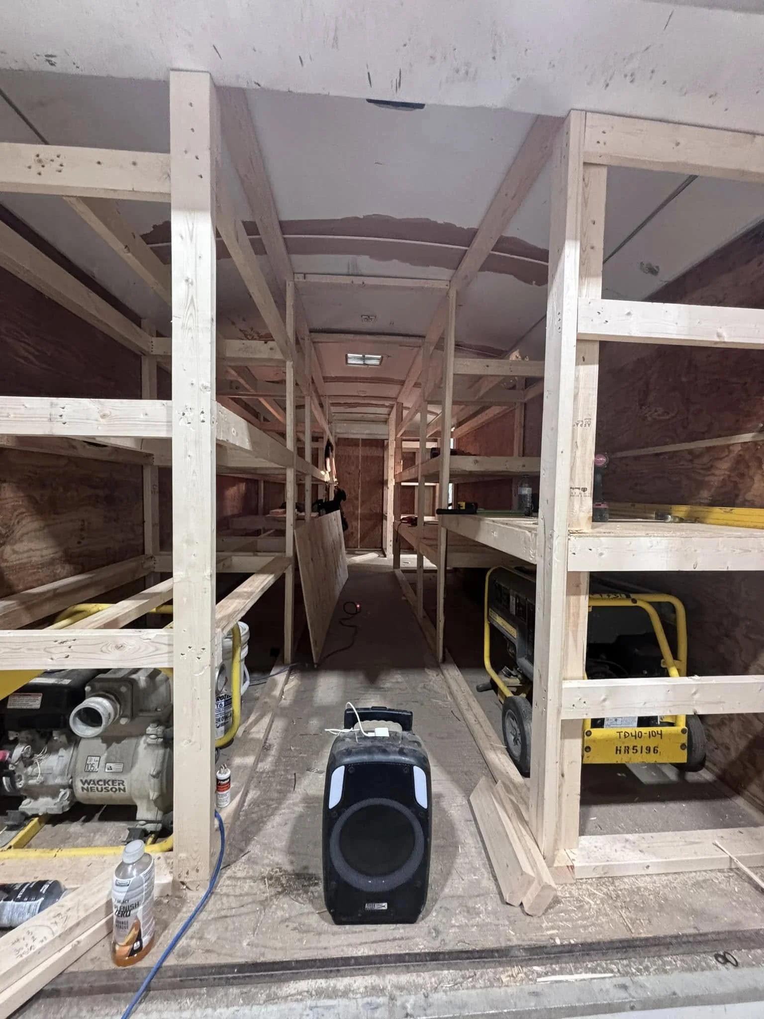 Construction site with wooden framing, power tools, and a portable speaker in the foreground.