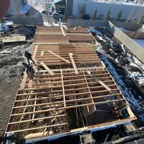 Construction workers building a wooden frame for a house foundation during winter.