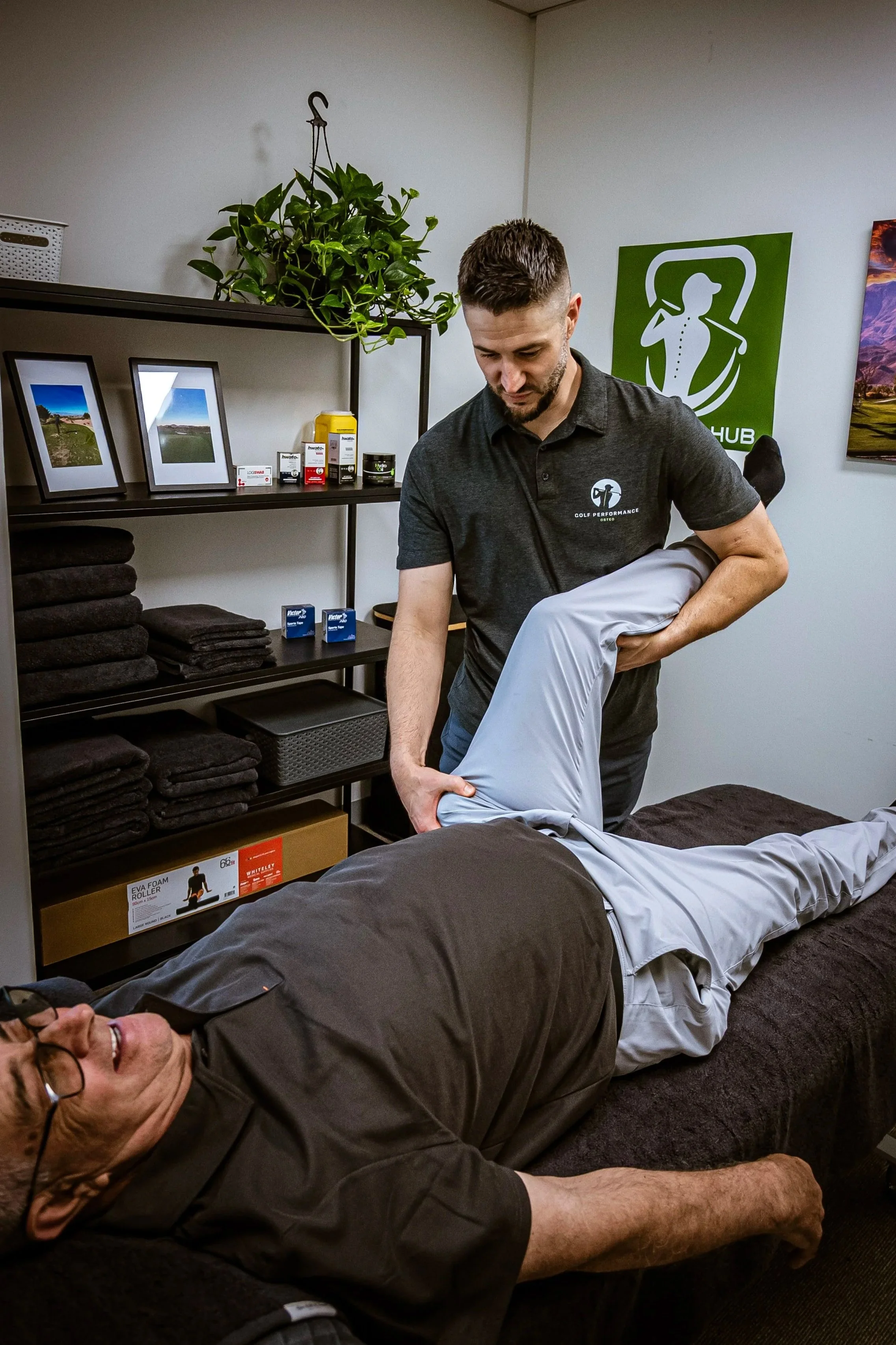 A man receiving a yoga or stretching session from a professional therapist in a therapy or wellness center.