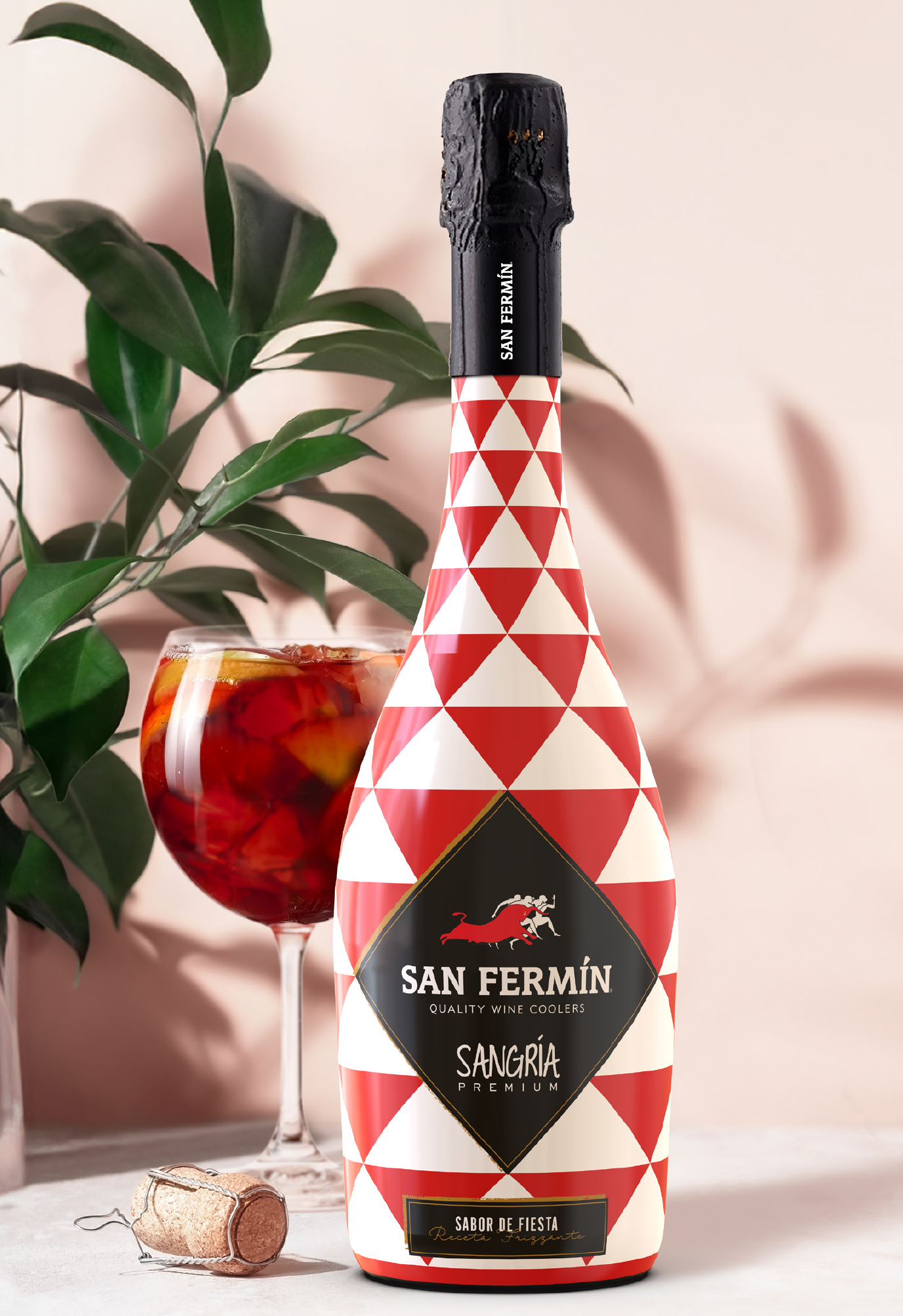Una botella de sangría San Fermín con un vaso lleno de sangría y fruta en un fondo decorativo con plantas.