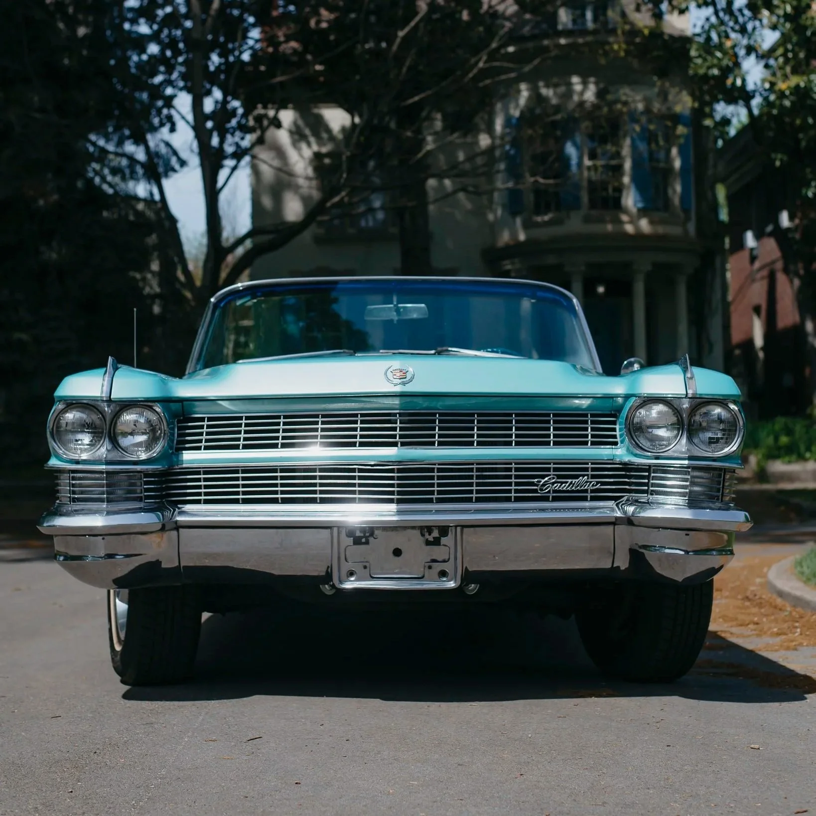 Front view of Charlene, a 1964 Cadillac Eldorado convertible, parked on a street with trees and houses in the background.