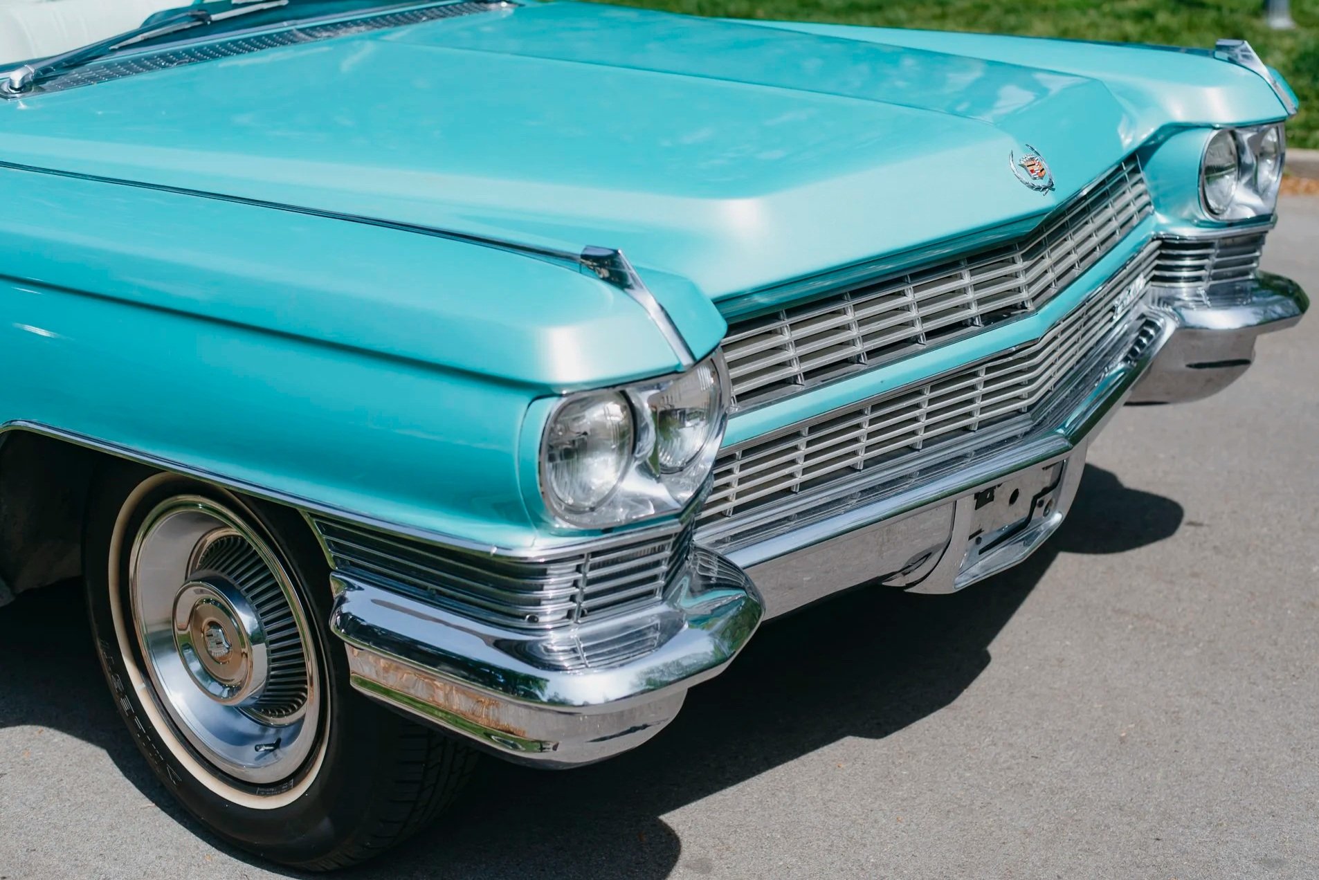 Front view of Charlene, a 1964 Cadillac Eldorado convertible, in turquoise color with chrome detailing and a Cadillac emblem on the hood.