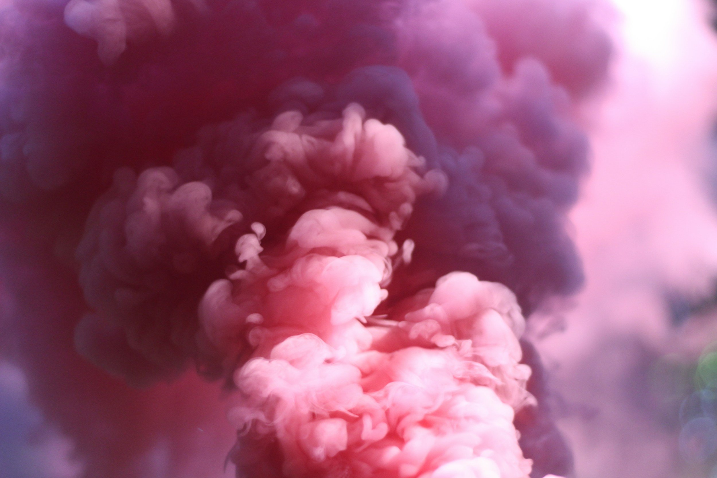 Colorful swirling cloud of pink, purple, and dark blue smoke or ink in water.