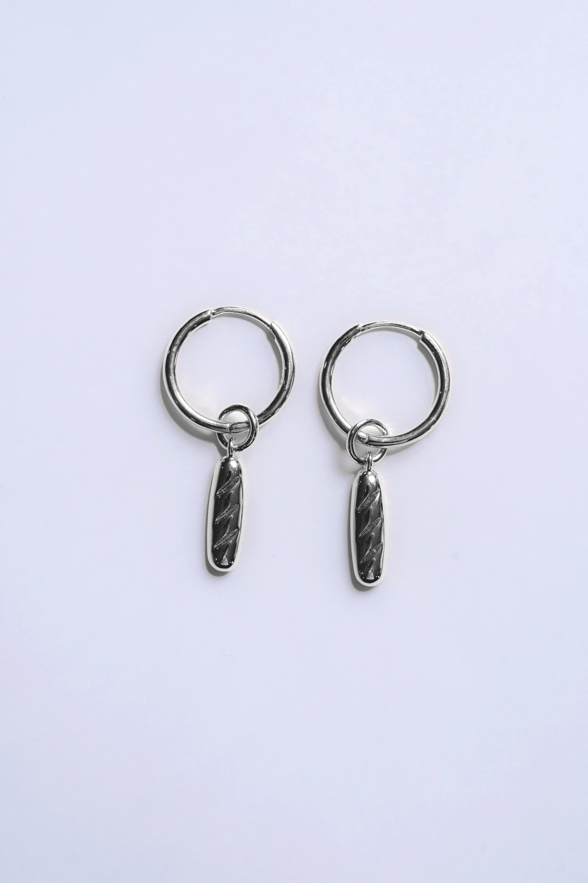 Pair of silver hoop earrings with rectangular dangling charms on a white background.