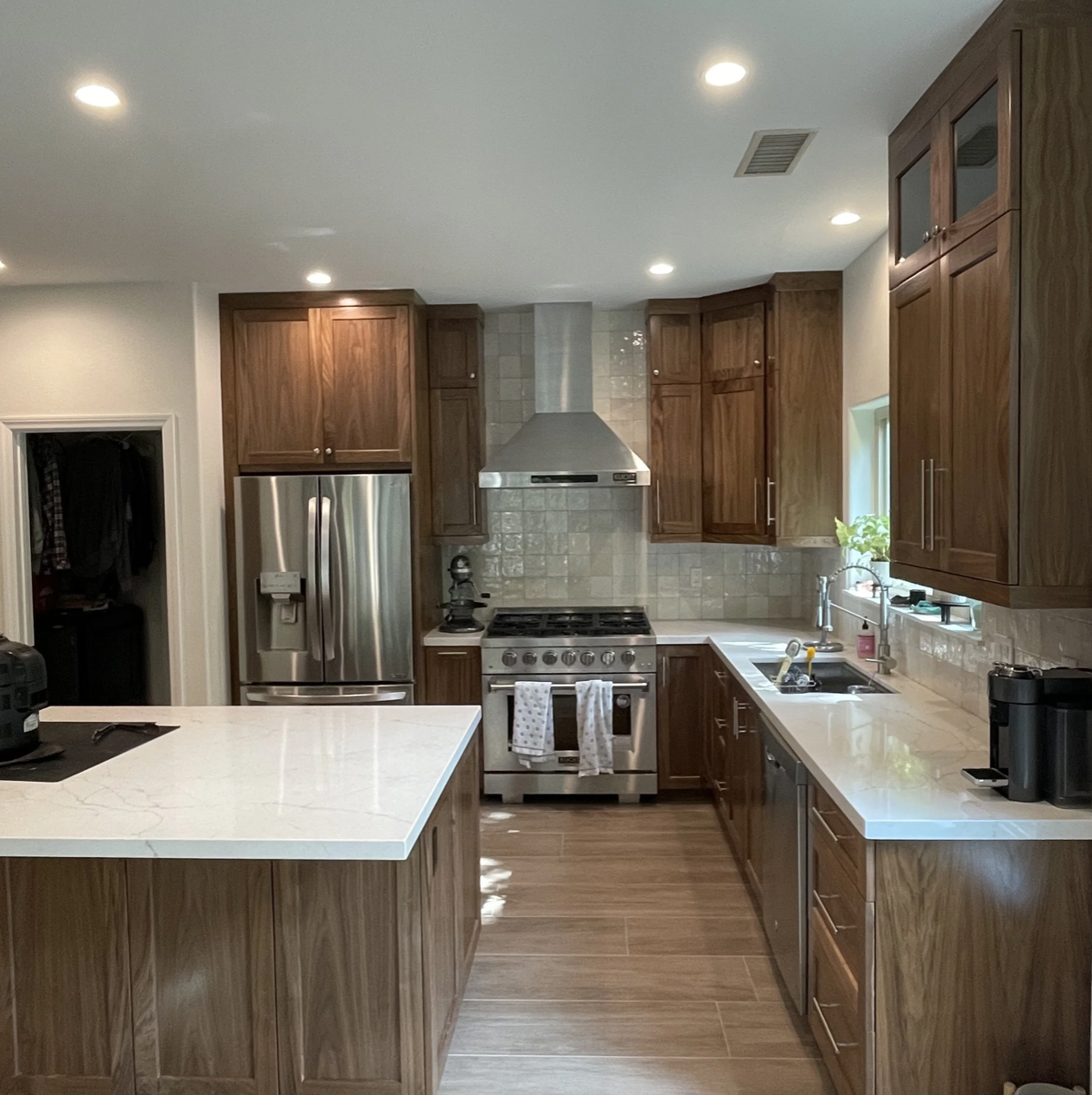 Modern kitchen with wooden cabinets, stainless steel appliances, a marble kitchen island, and a tiled backsplash.
