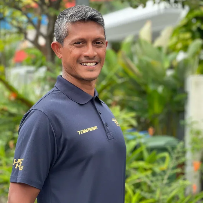 Man smiling outdoors wearing a navy blue polo shirt.