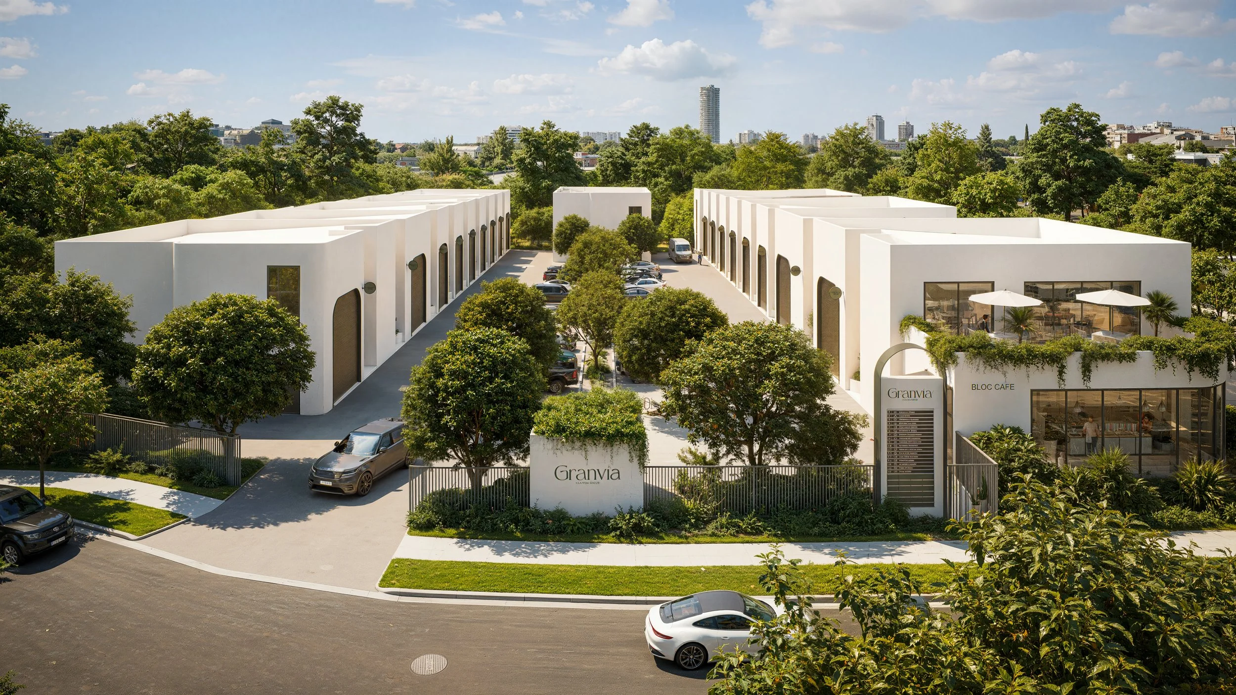 Aerial view of a modern white commercial or residential complex with two wings, parking lot, lush greenery, and a restaurant with outdoor seating, labeled 'Granvia', in an urban setting with trees and high-rise buildings in the background.