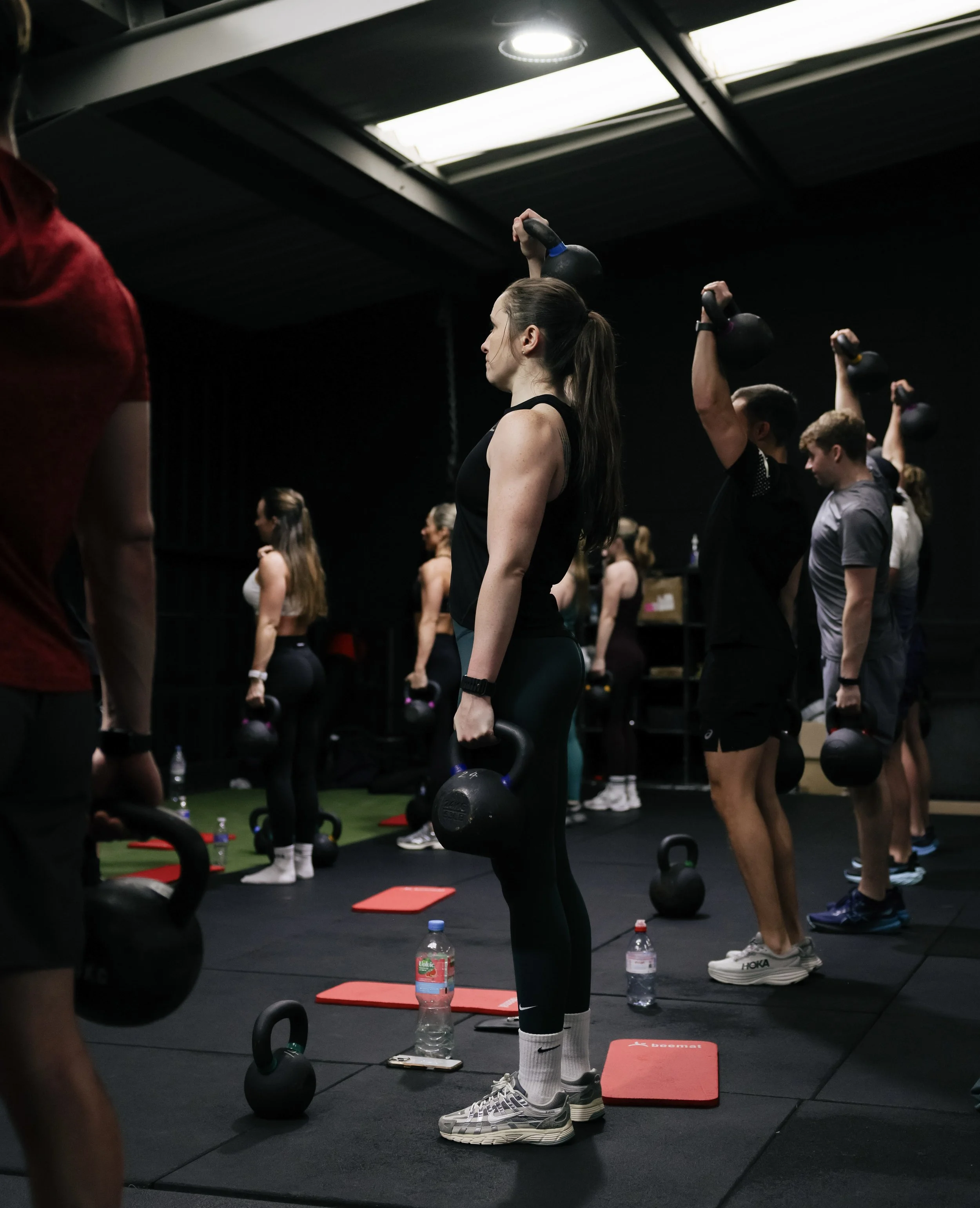 Group fitness class performing kettlebell exercises in a Liverpool gym.