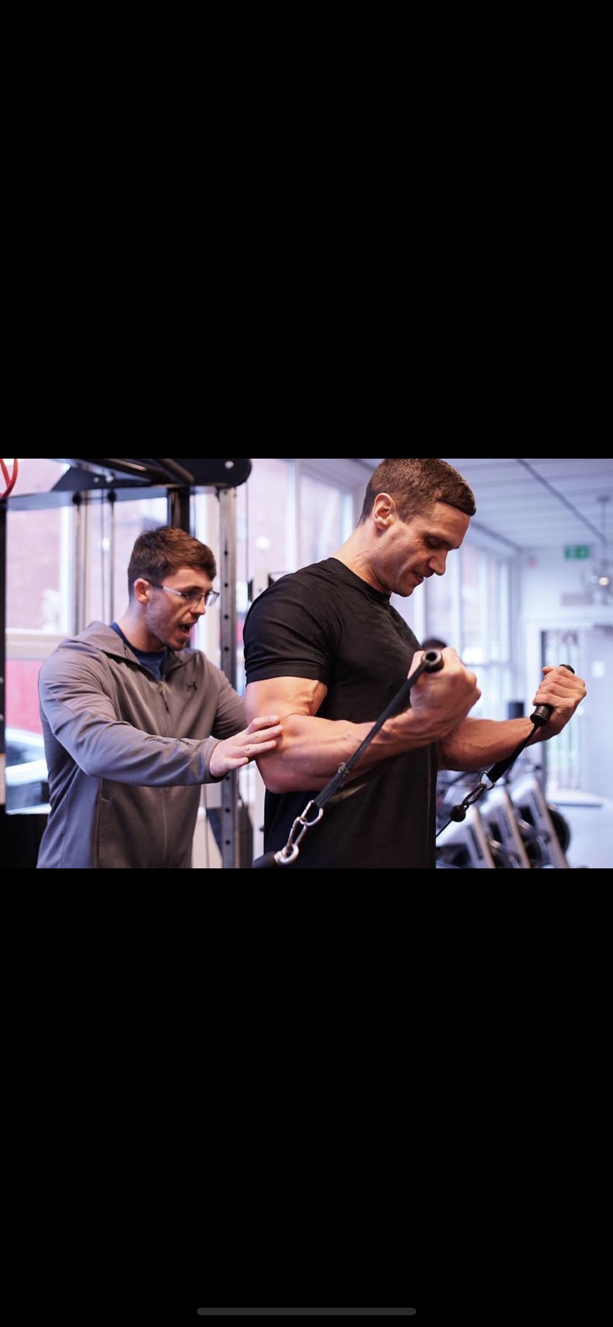 Personal trainer guiding a client through a cable machine workout during a one-on-one training session.