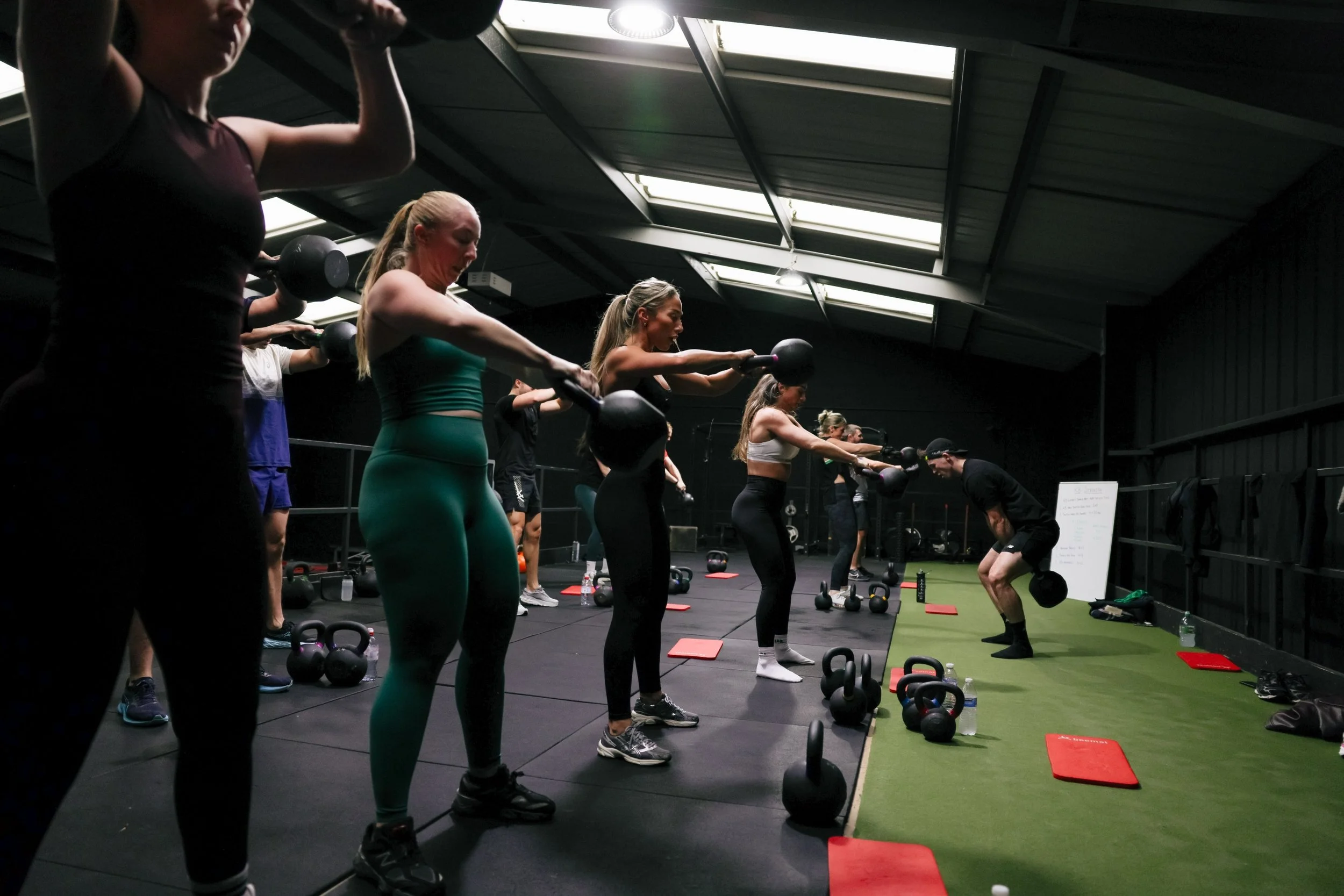 Group performing kettlebell swings during a coached class at Raise The Bar Gym in Speke Liverpool