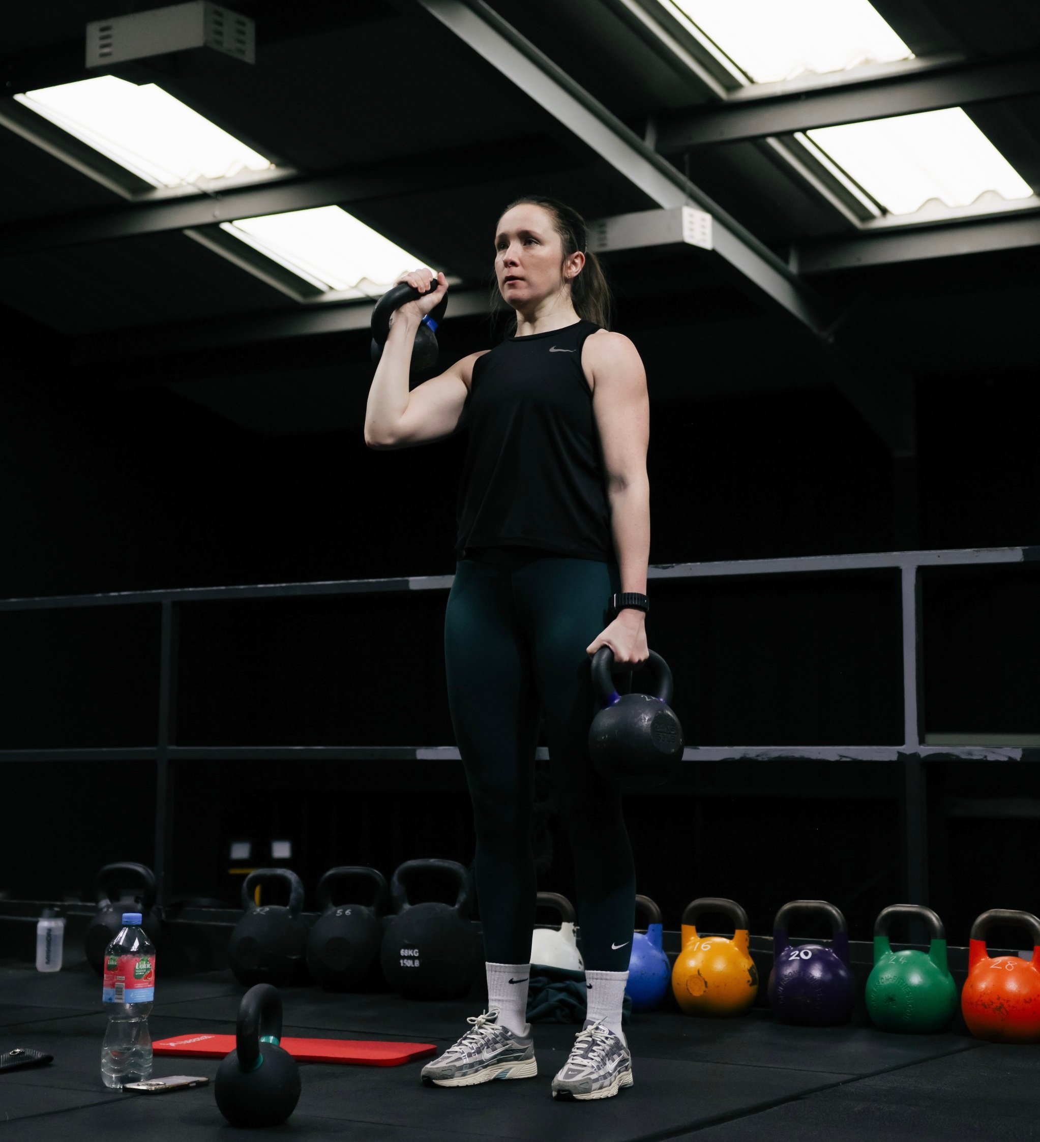 Woman performing kettlebell clean in gym during beginner strength training session
