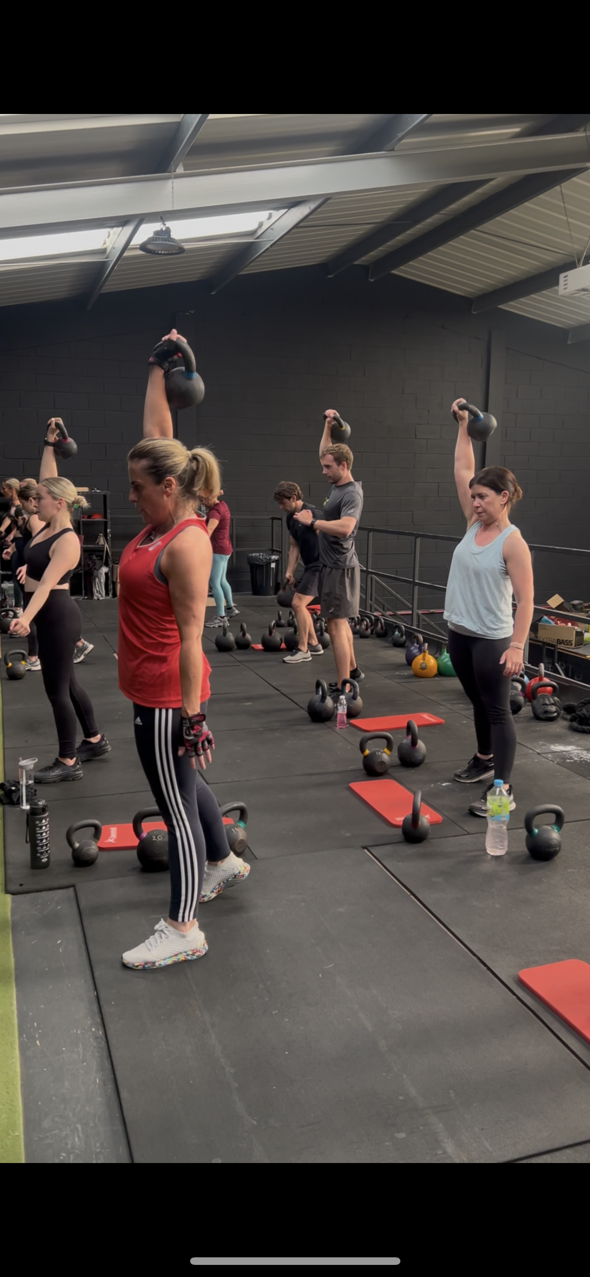 Group of people lifting kettlebells in a gym with text reading “All Classes.”