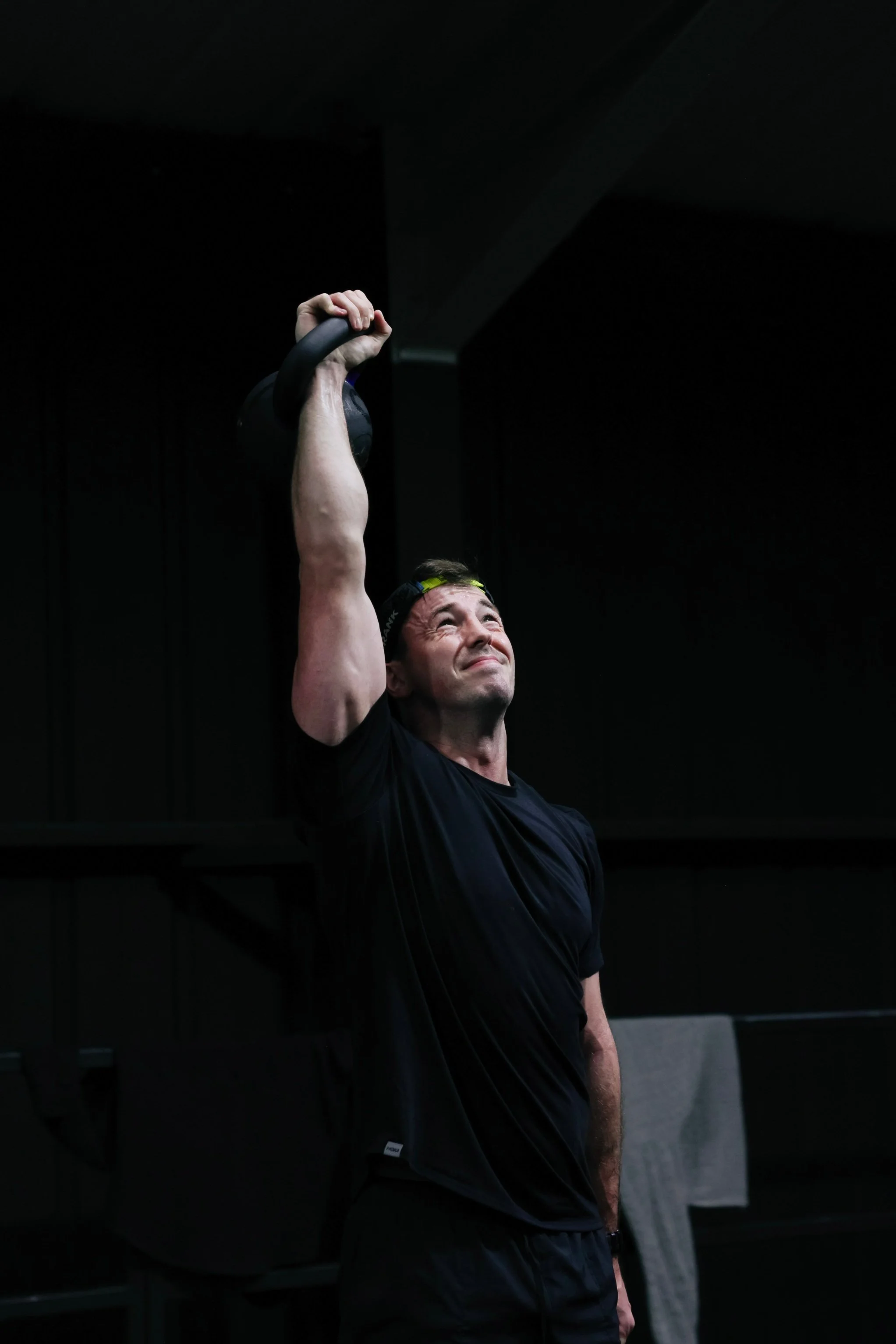 Personal trainer performing a single-arm kettlebell overhead press during a strength and conditioning workout.