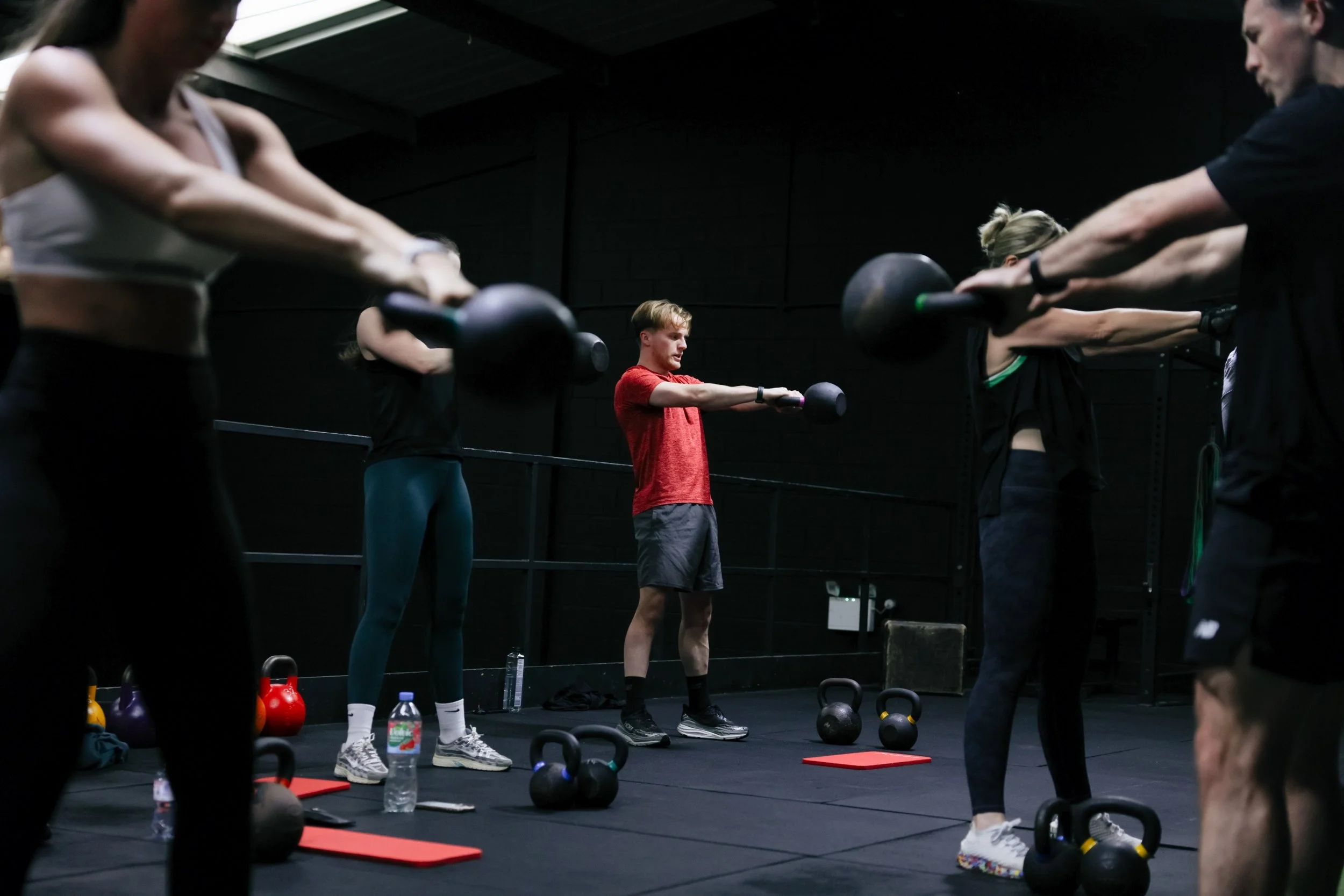 Coach guiding kettlebell swing technique during a small group training session in Speke Liverpool