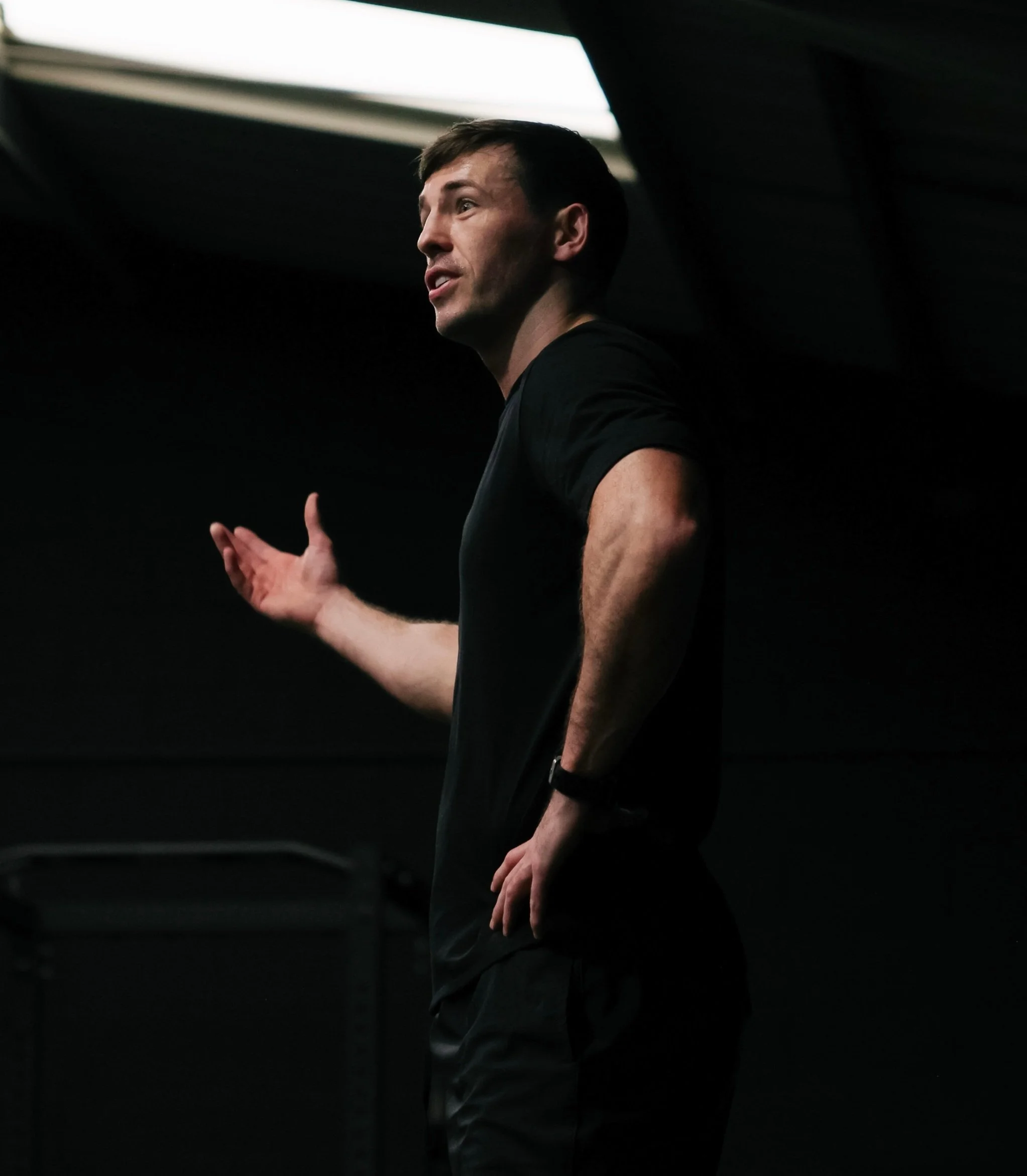 Personal trainer speaking and gesturing during a consultation in a gym.