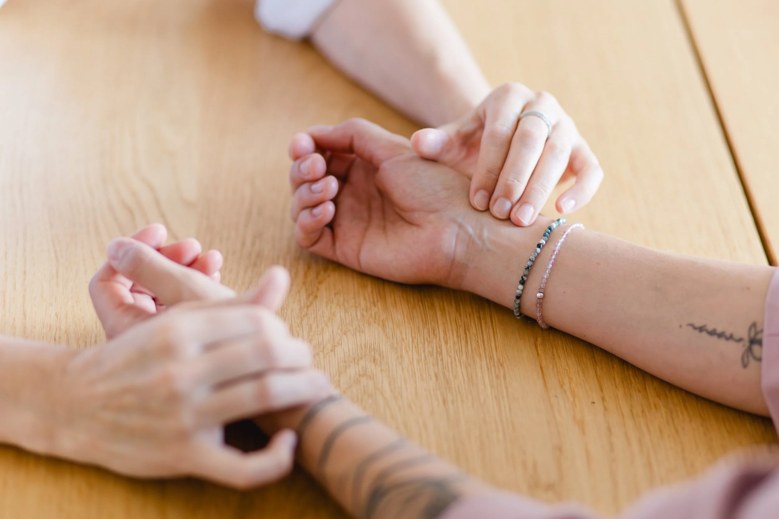 Nahaufnahme von Dr. Petra Nöbauer und den Händen der Patientin zur Pulsdiagnostik