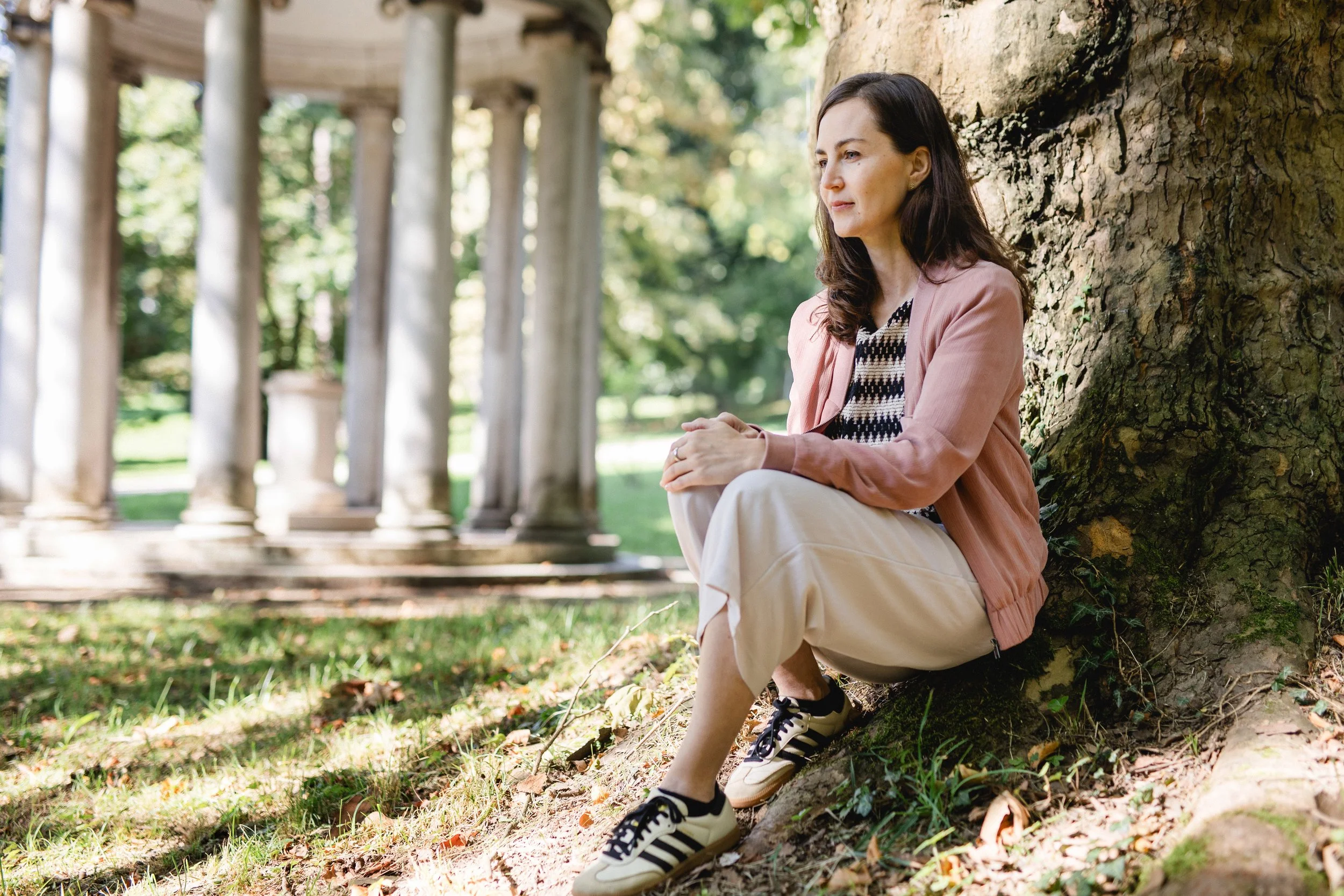 Dr. Petra Nöbauer lehnt an einem kräftigen Baumstamm inmitten der Natur