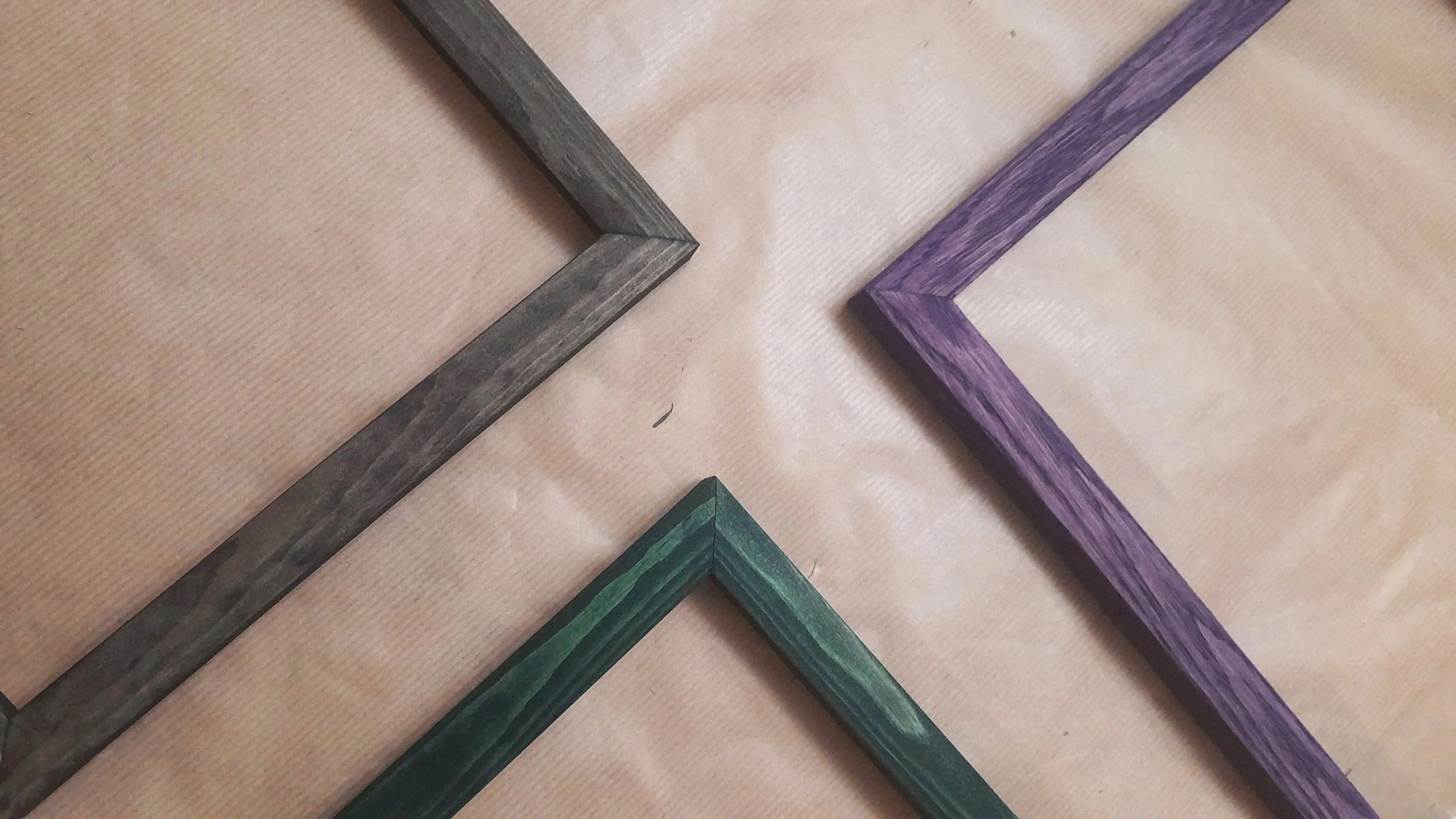 Colored picture frames in different shades of gray, green, and purple arranged on a wooden surface.