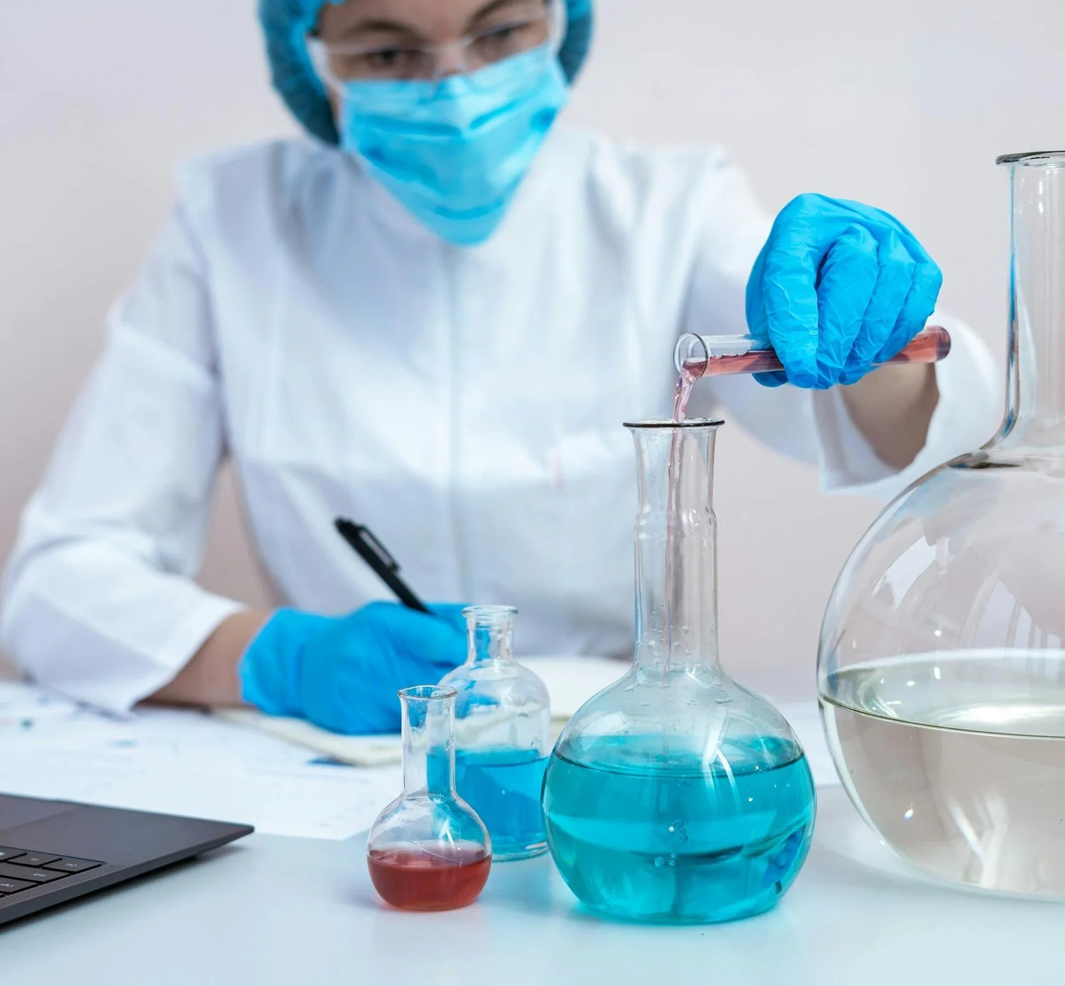 A forensic scientist wearing a face mask, goggles, gloves, and a protective suit conducts meth testing in laboratory.