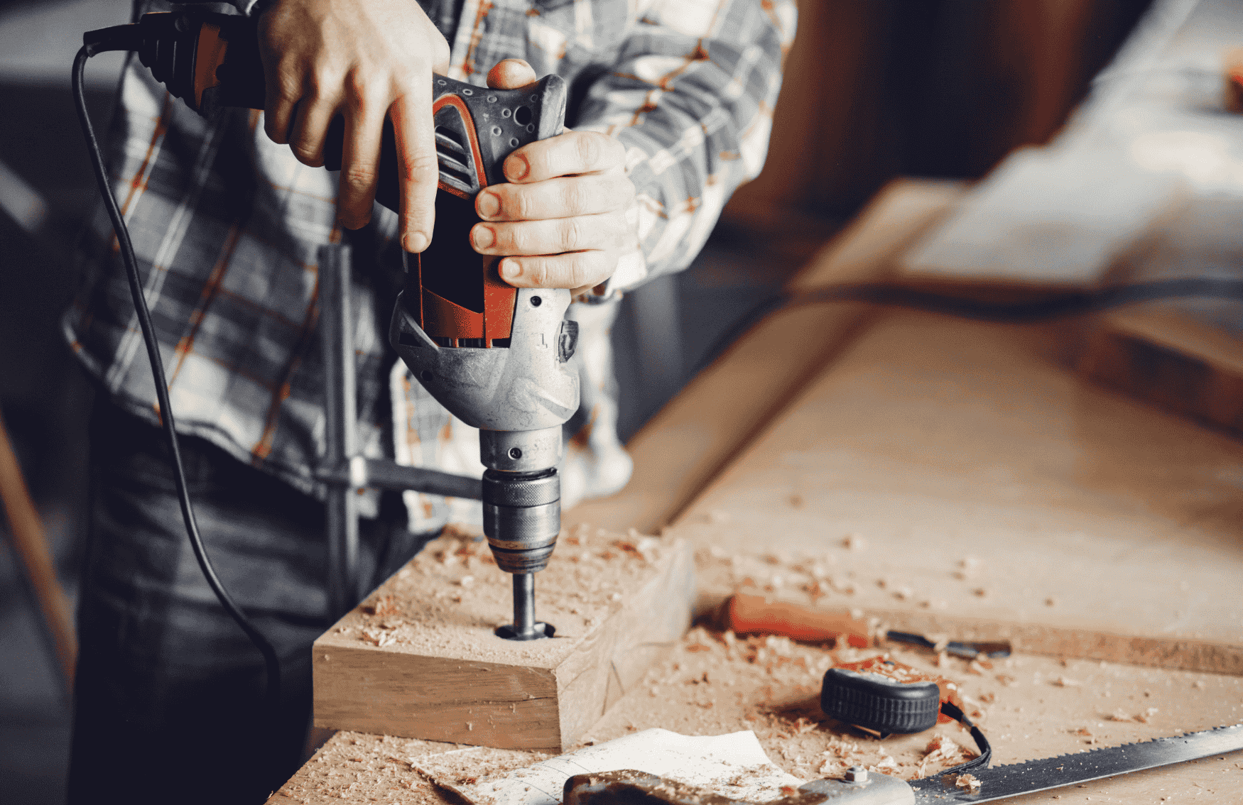 Carpenter using a power drill on timber in a joinery workshop