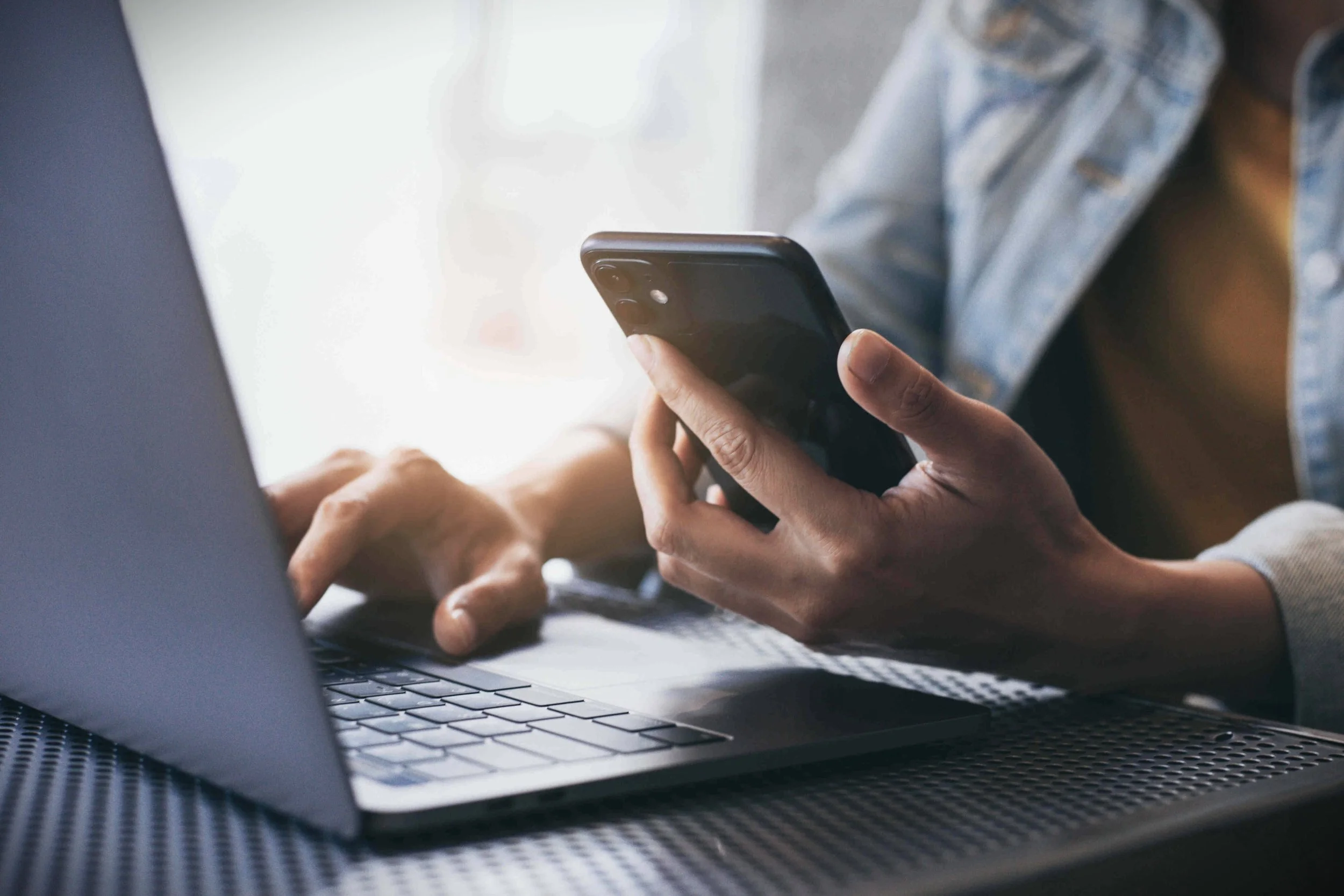 Person using smartphone and laptop – contact Datum Works for joinery and construction services UK