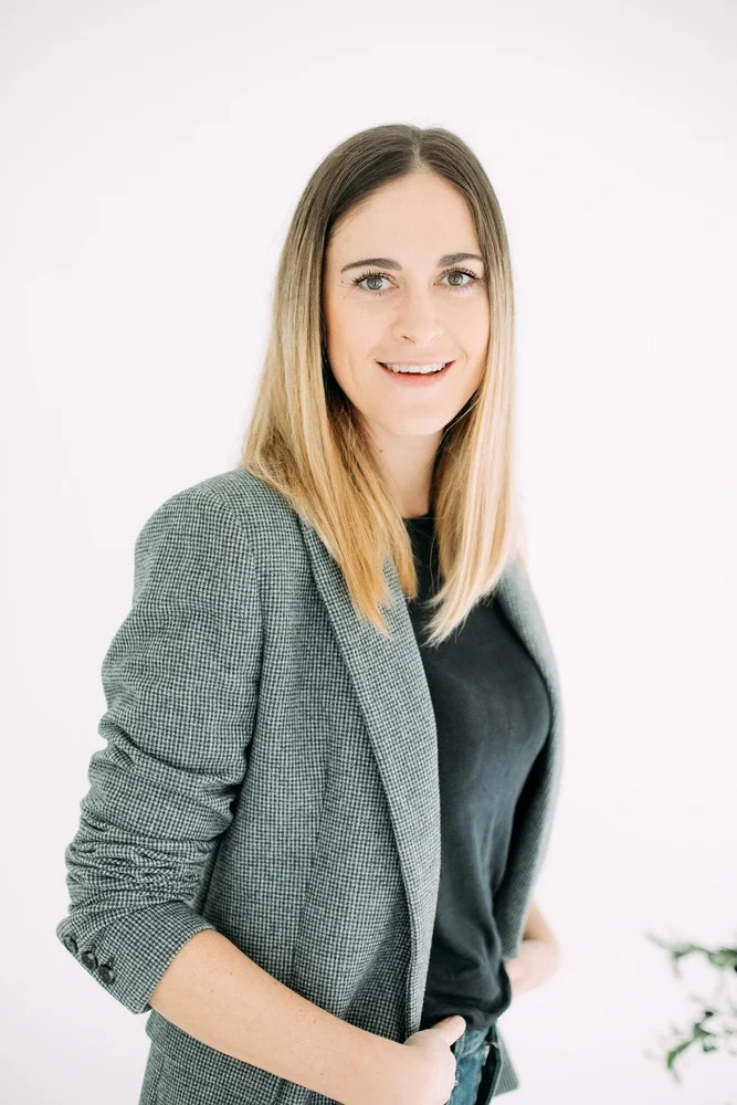 Jade Mac Sweeney, coache de vie certifiée, jeune femme blonde, debout, porte un blazer gris