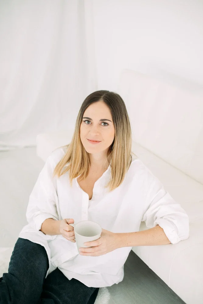 jade mac sweeney, coache de vie certifiée, assise, jeune femme blonde, chemise blanche, tient une tasse de café