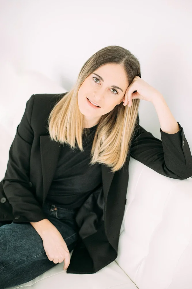 jade mac sweeney, coaching trauma, jeune femme blonde, blazer noir, assise sur un canapé